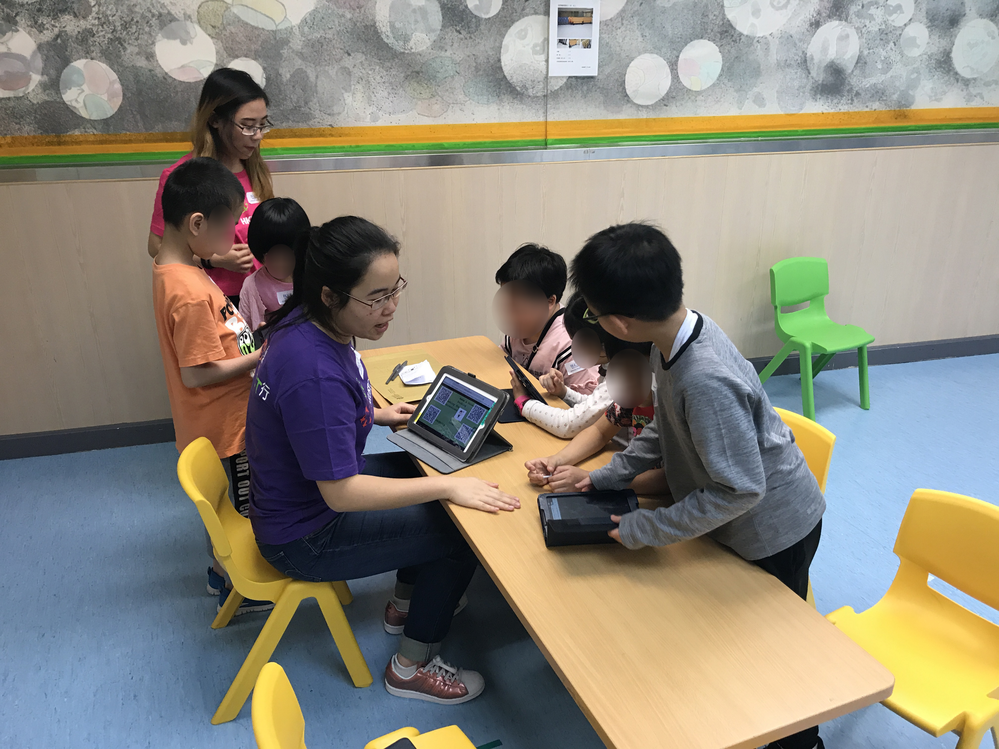Volunteer guiding children to use tablets to play the games