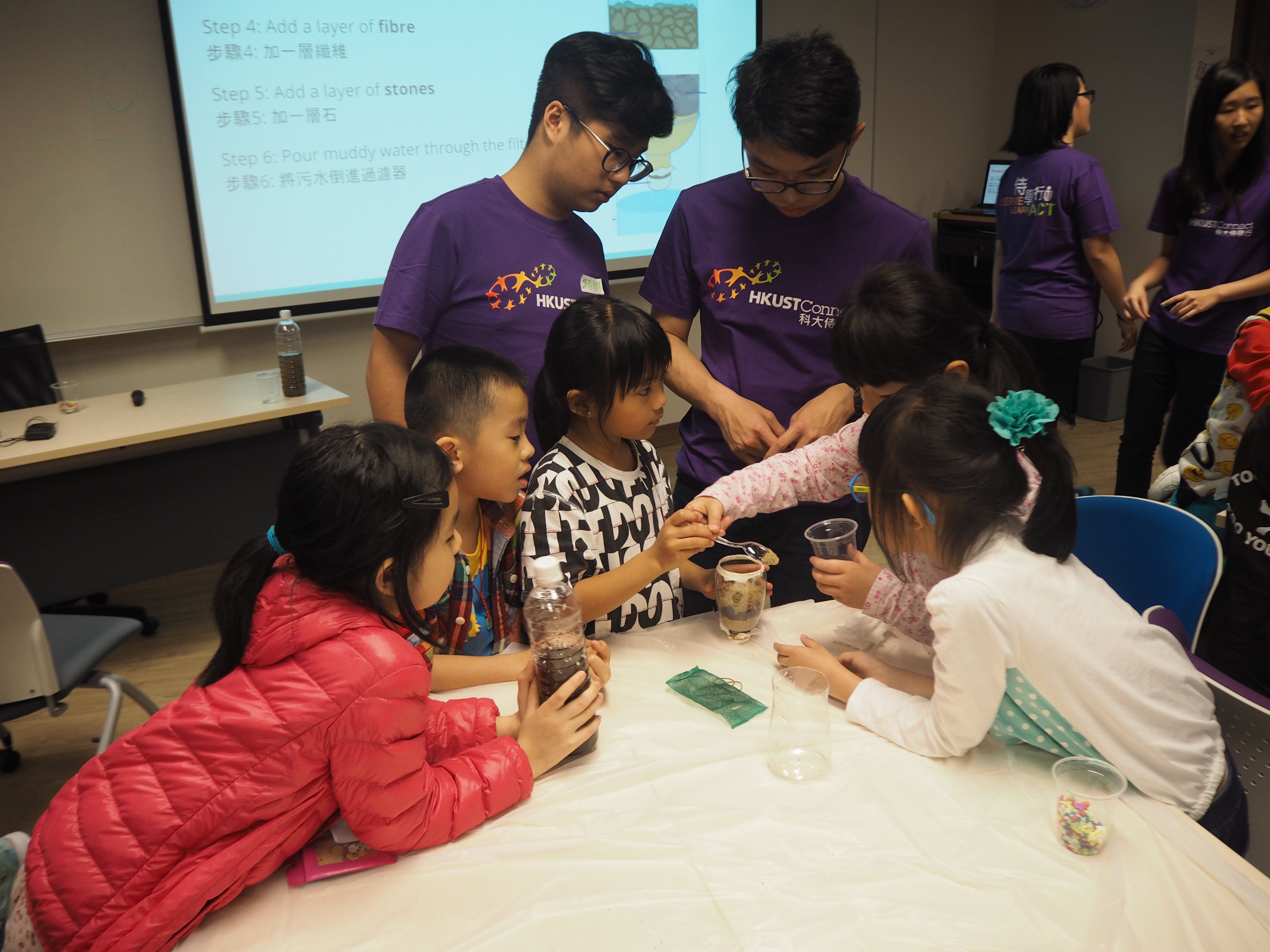 Volunteers guiding children in doing experiment