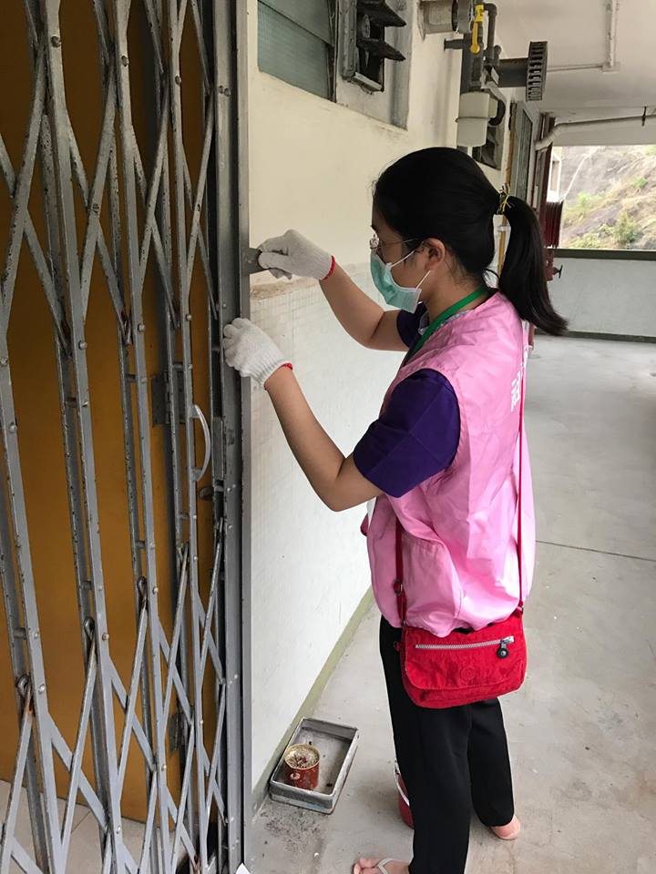 Volunteer removing rust from a gate