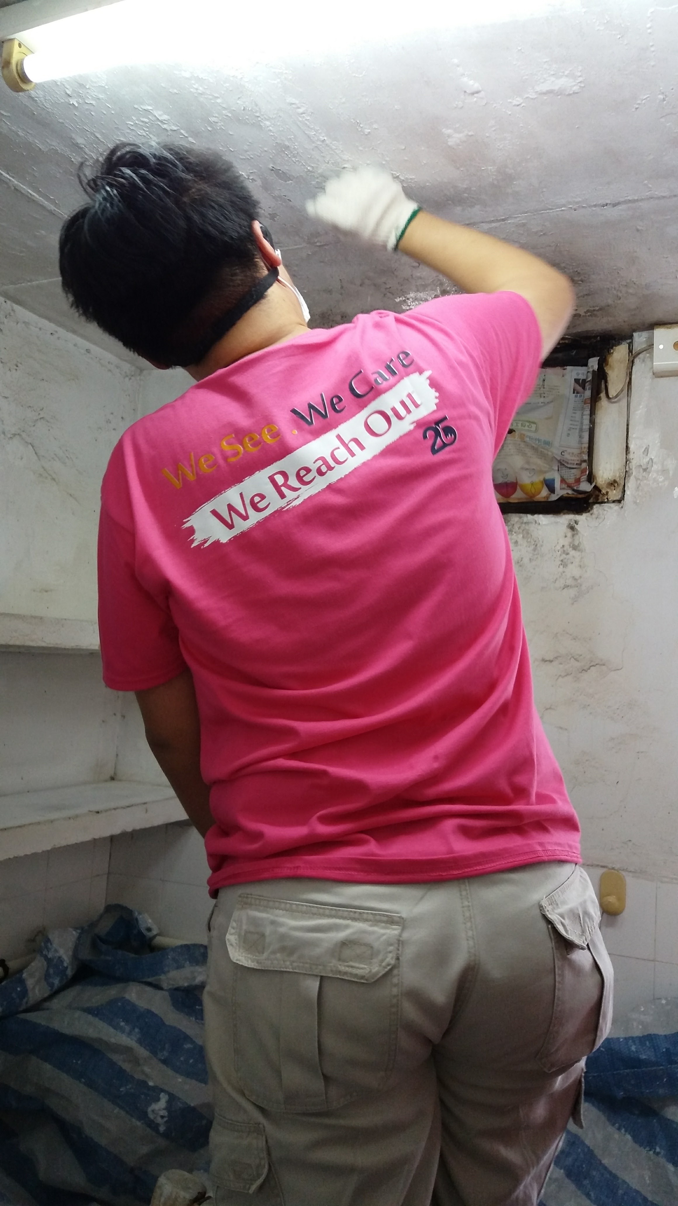 A volunteer fixing a peeling ceiling