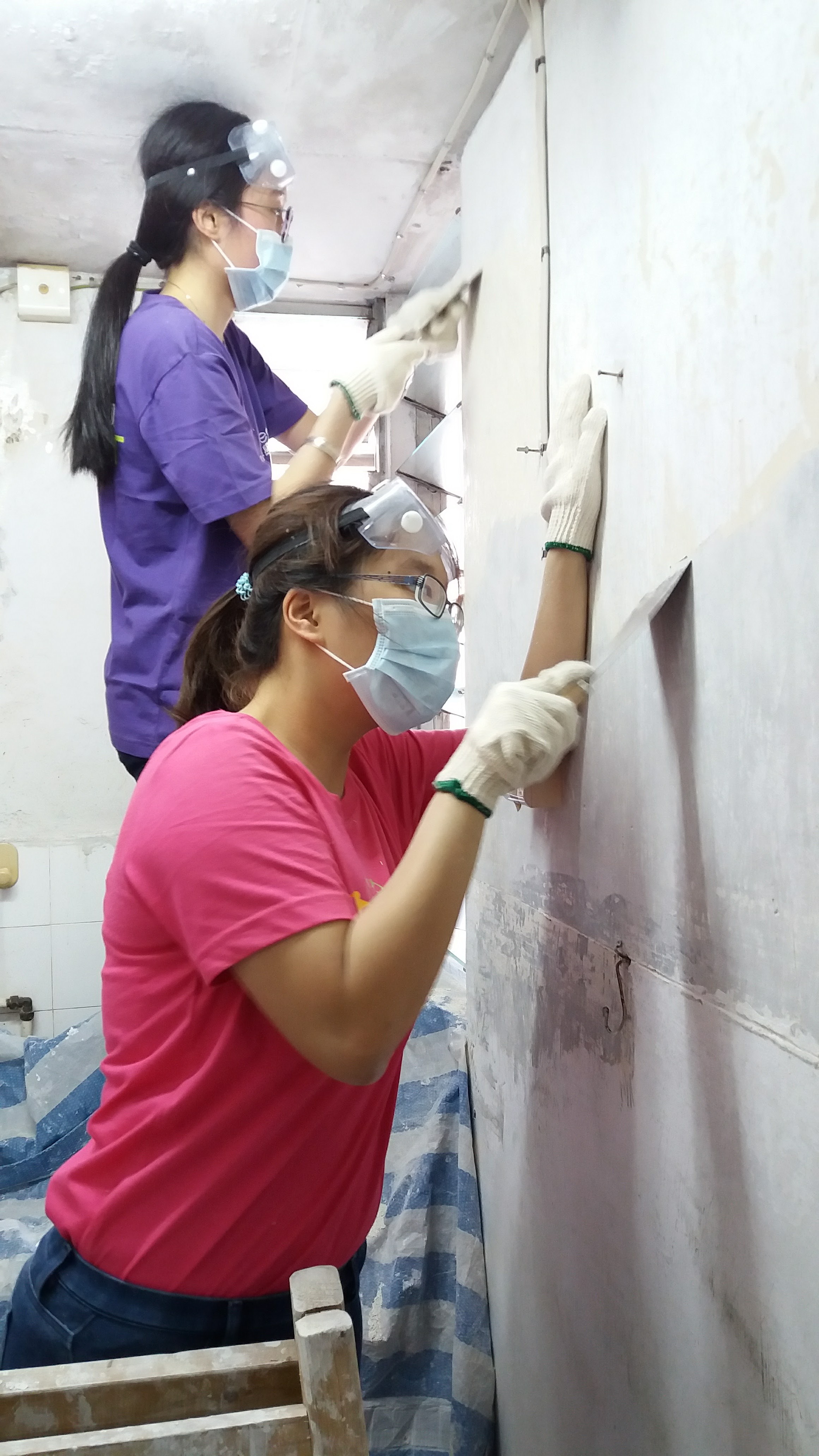 Volunteers removing uneven wall plastering