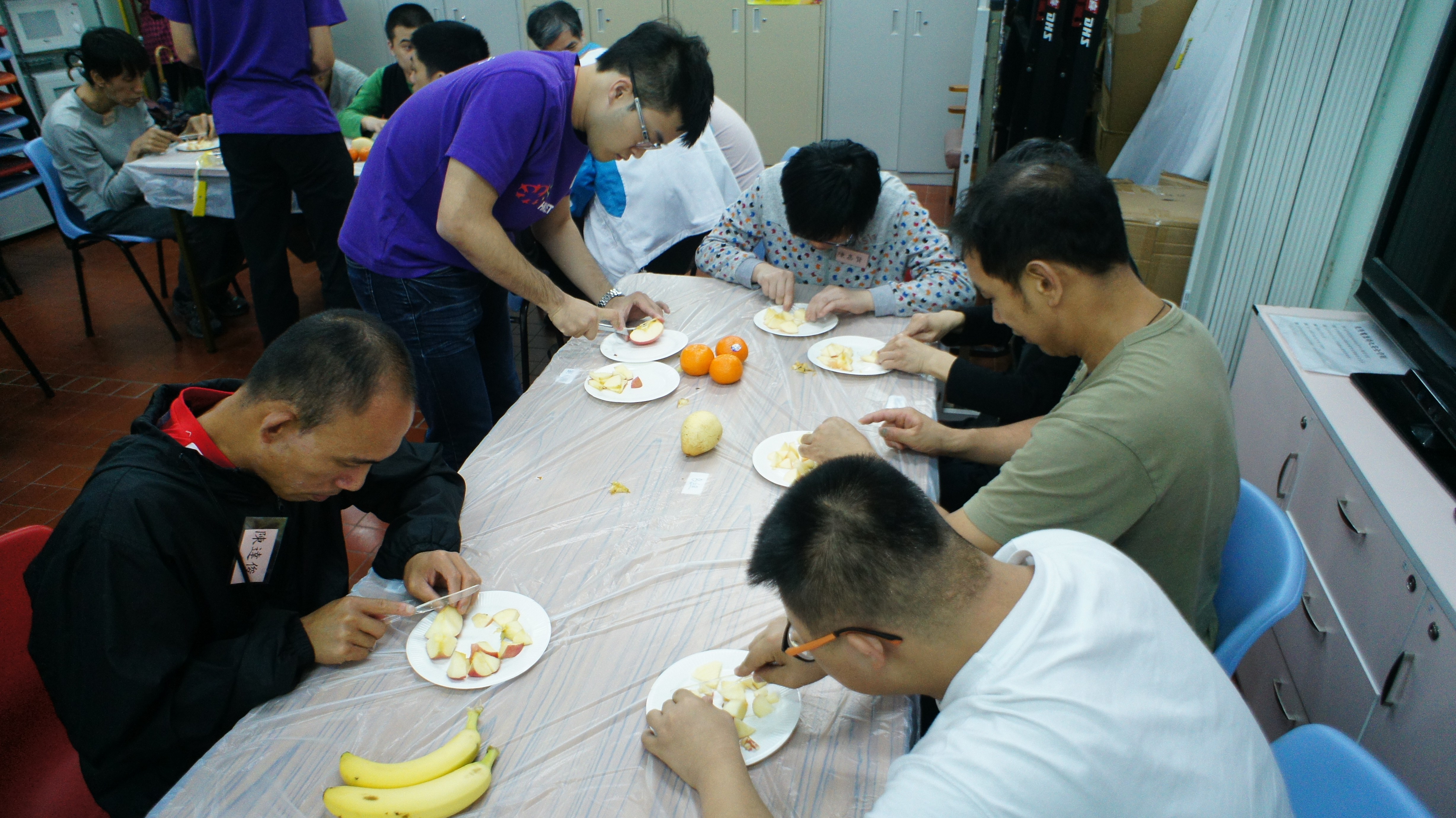Volunteers teaching the service recipients to prepare simple fruit salad and sandwiches