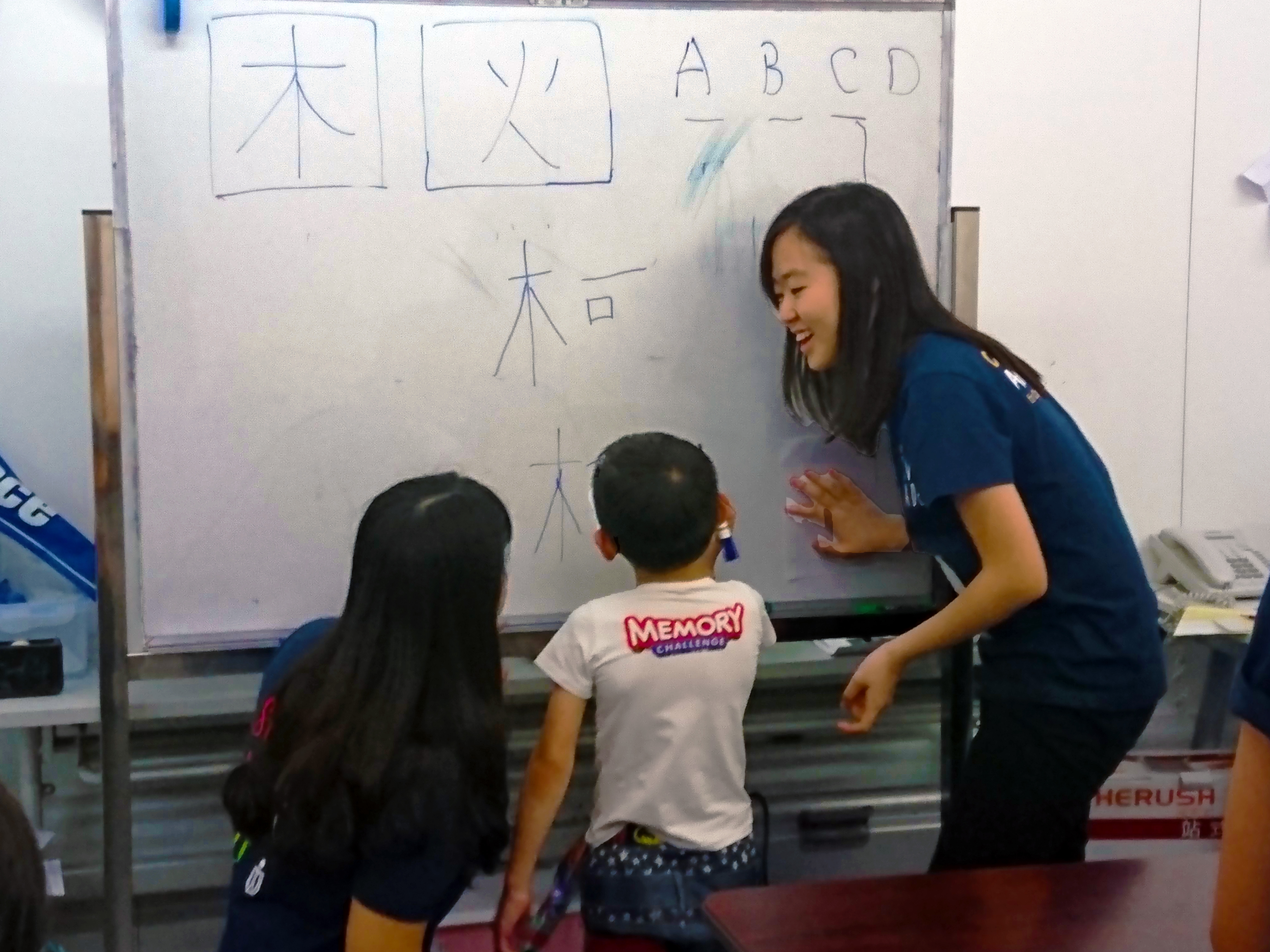 Volunteers teaching the children to write Chinese word