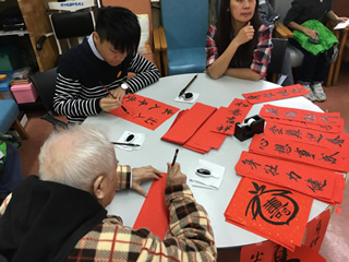 Volunteer writing fai chun with the elderly