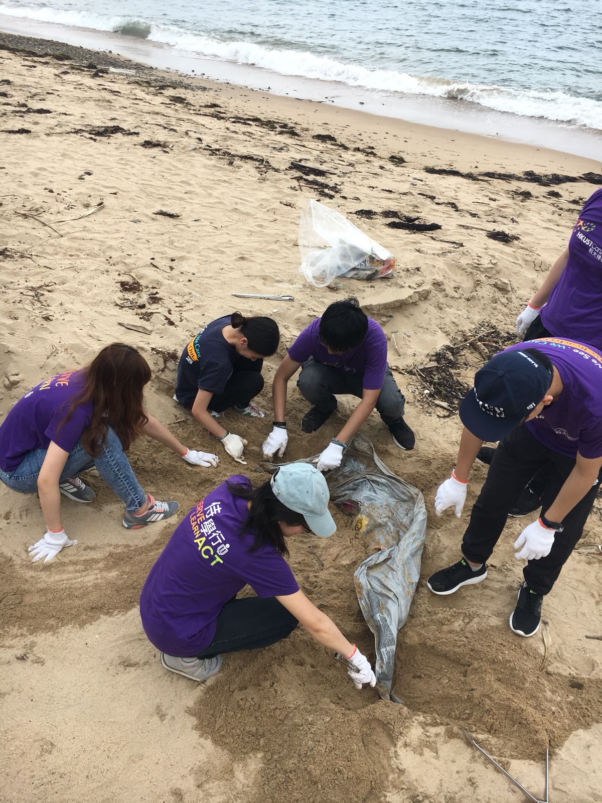 Volunteers digging out a big piece of plastic