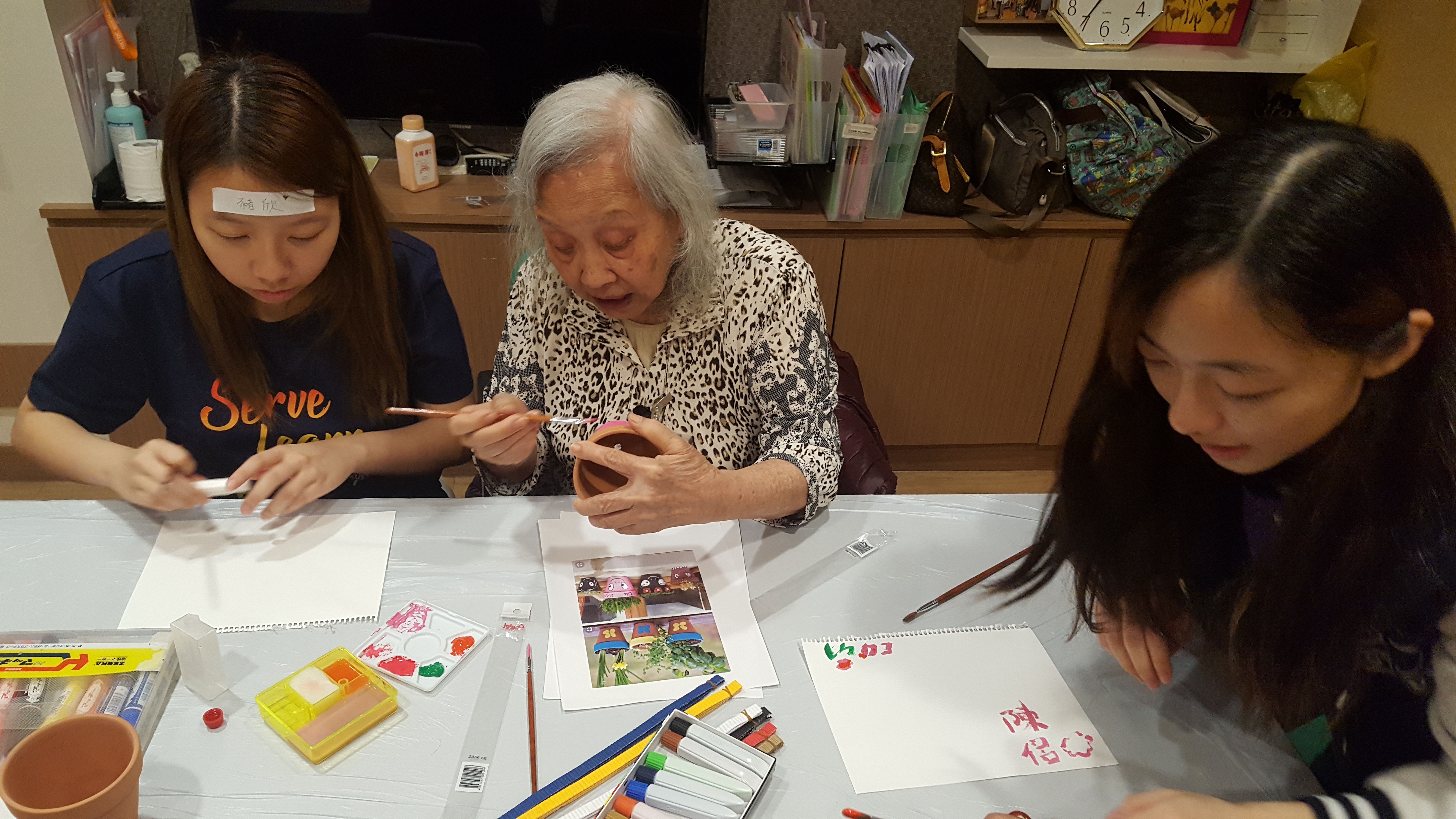 Volunteer and elderly making pot decorations