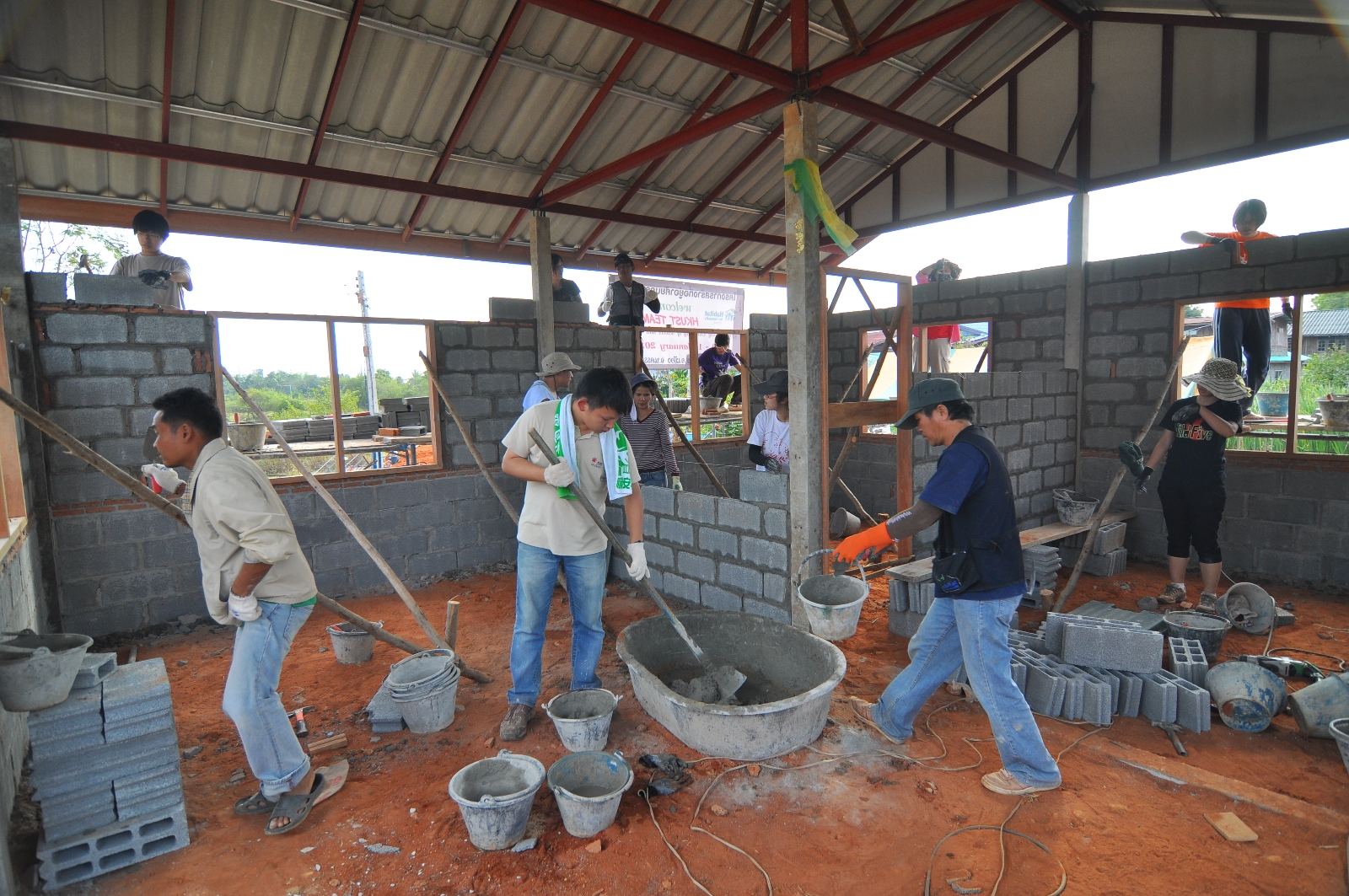 Student volunteers mixing cements and laying bricks