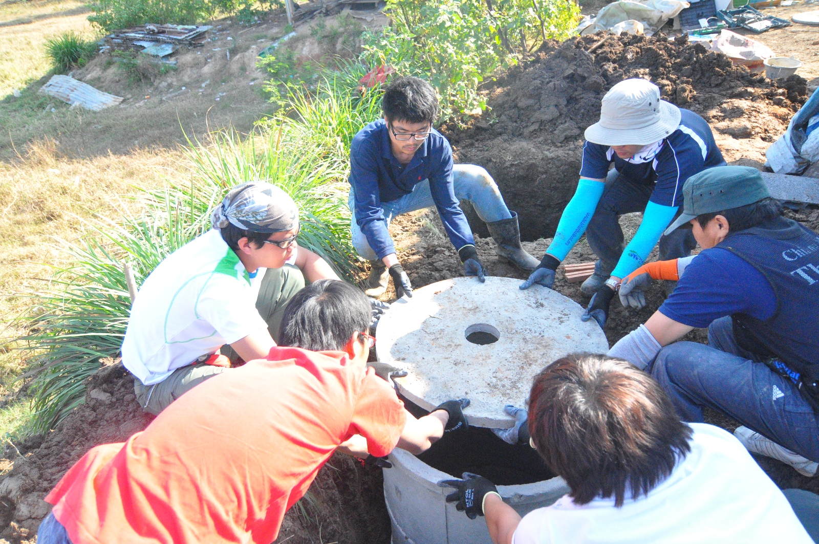 Student volunteers closing lid of the septic tank