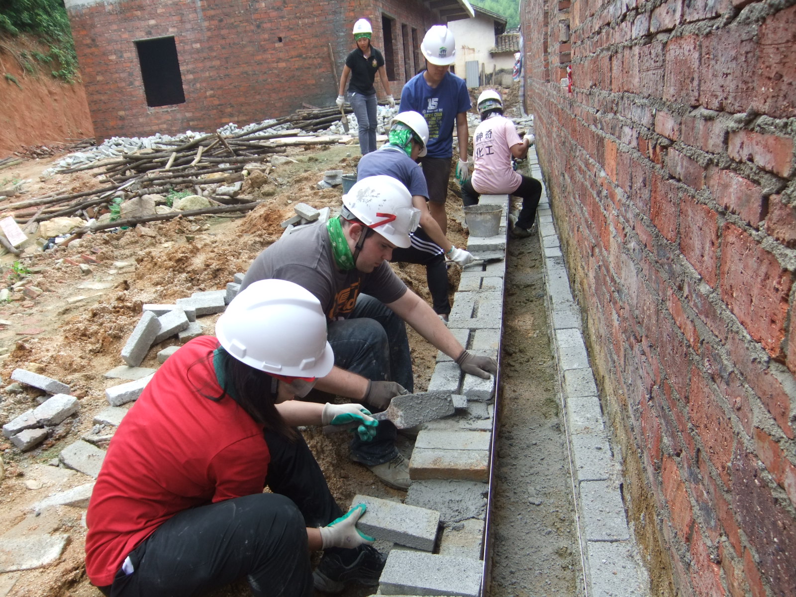 To make a staight wall, volunteers need to lay the bricks carefully!