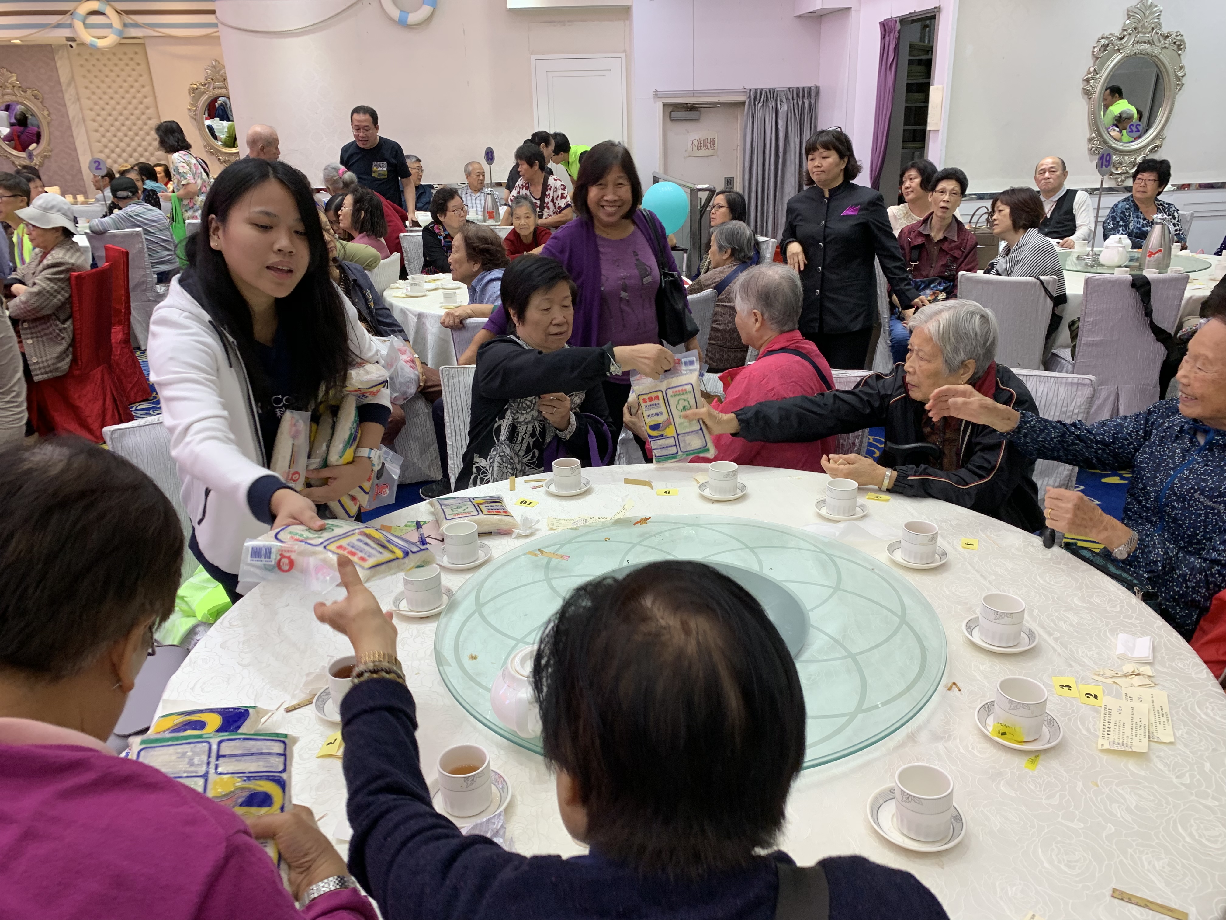 Volunteers passing gifts to the eldery round the table