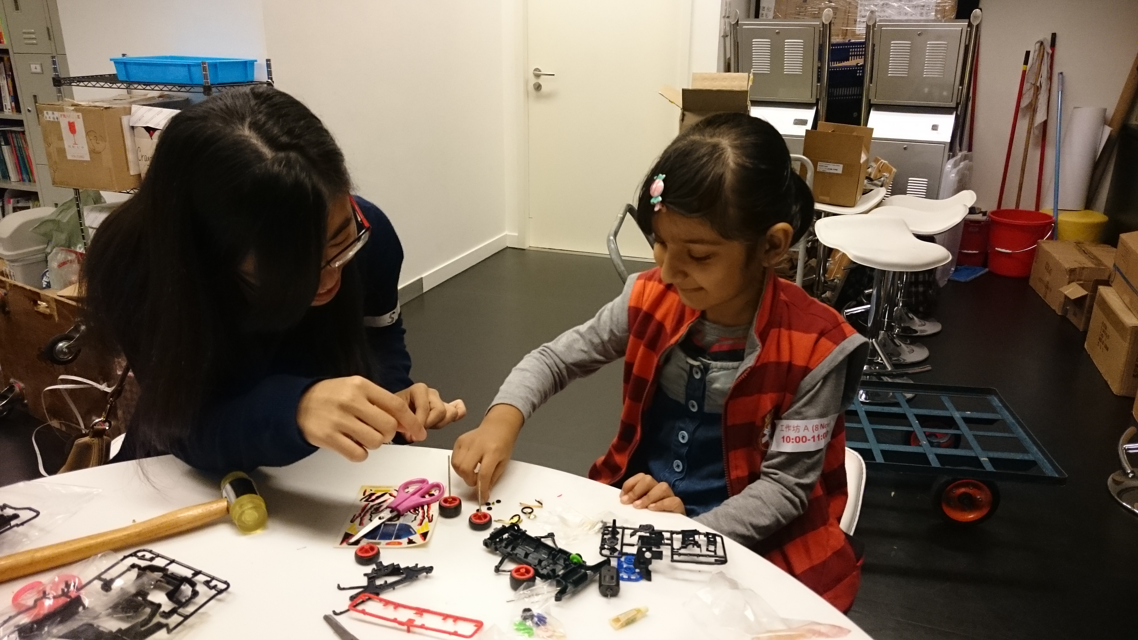Volunteers teaching a kid to make a car
