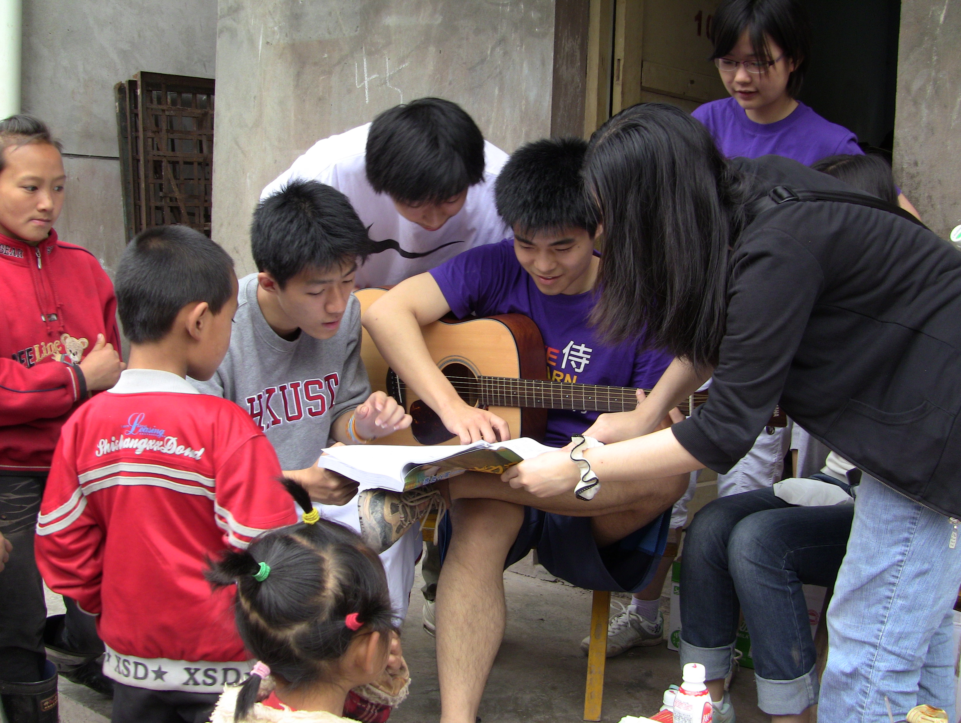 Volunteers playing guita and singing songs with the kids