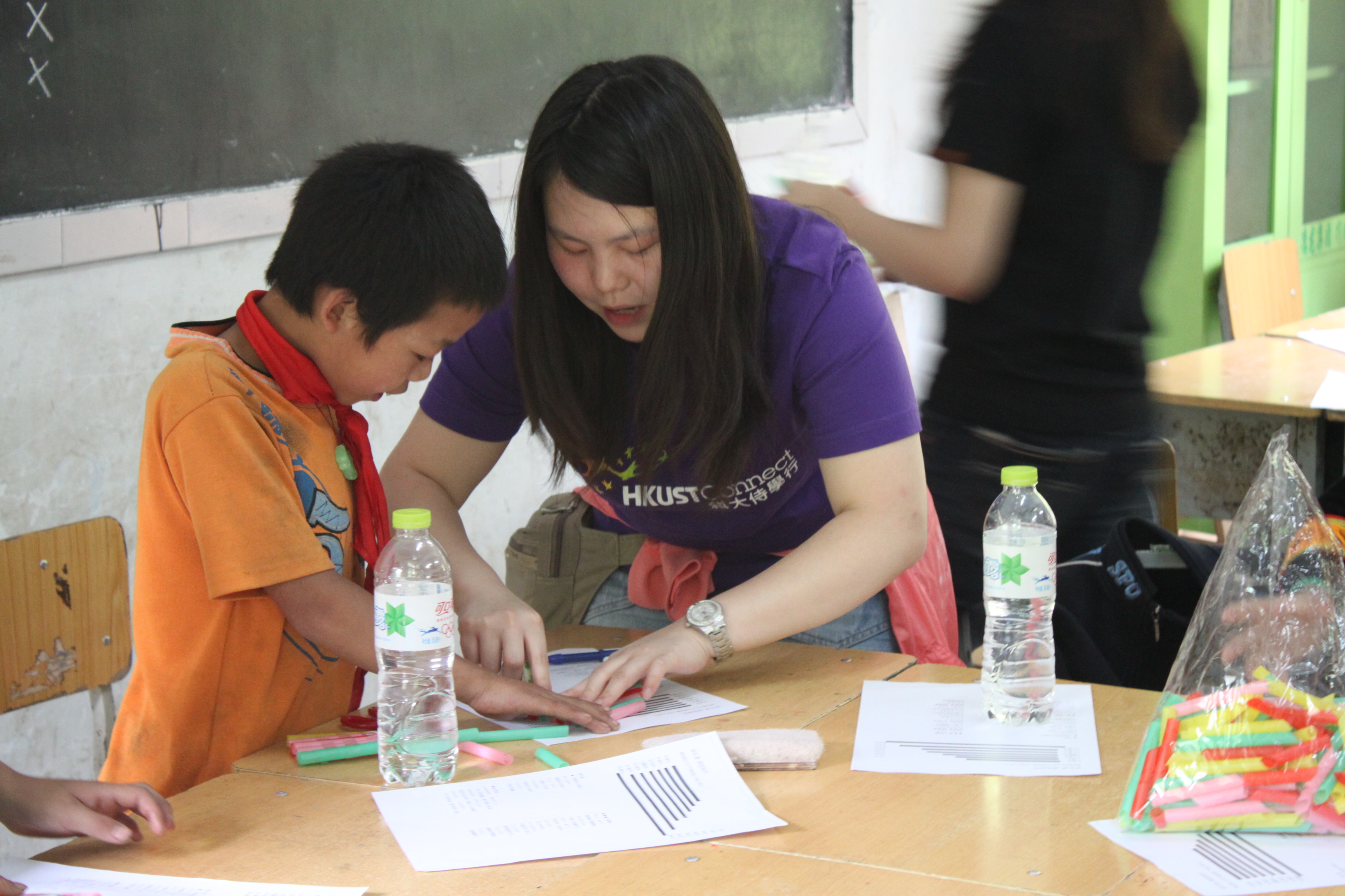 Volunteer helping the kid to make his own musical instrument