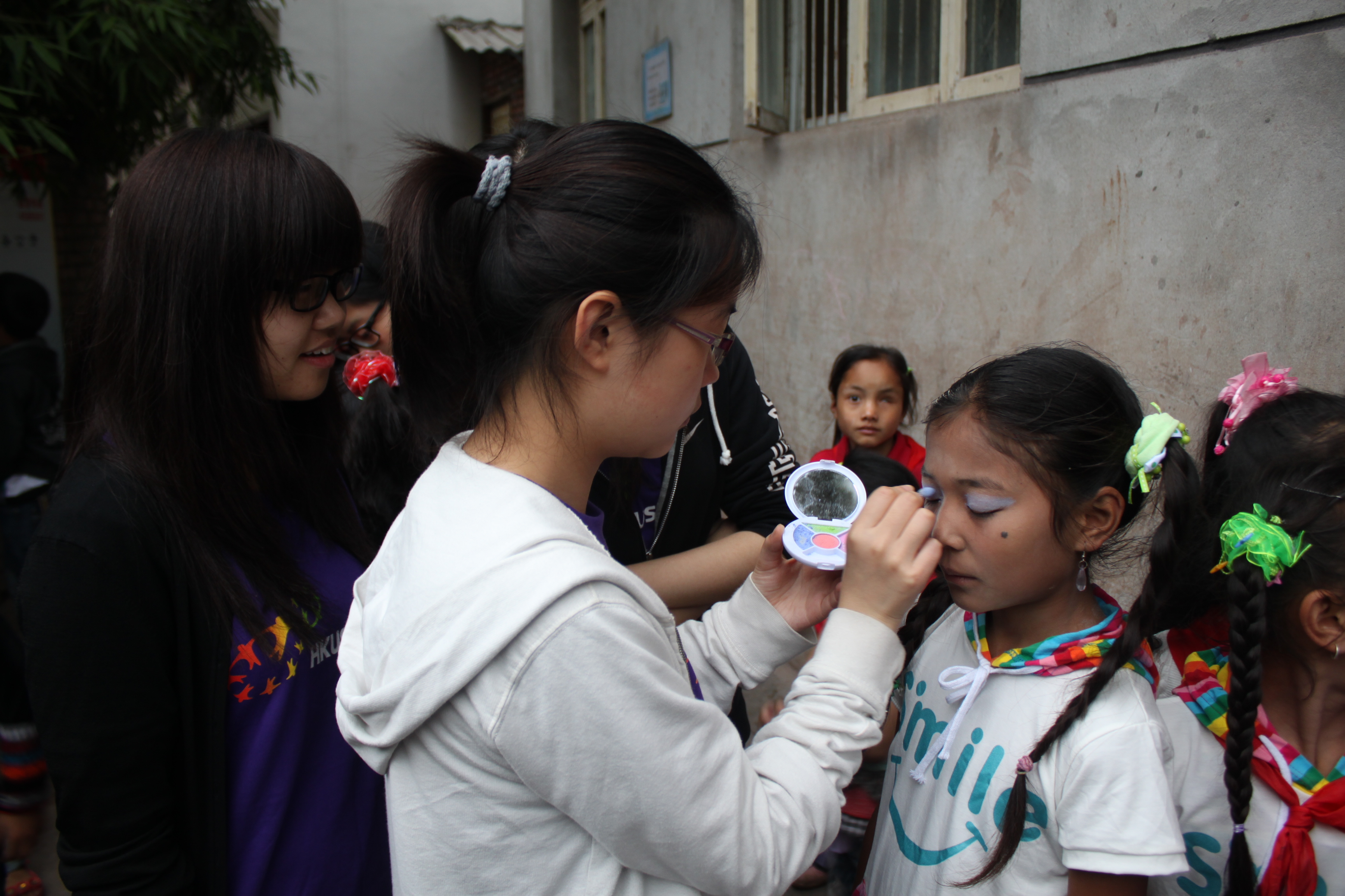 Volunteers helping childern to wear makeup for their performance