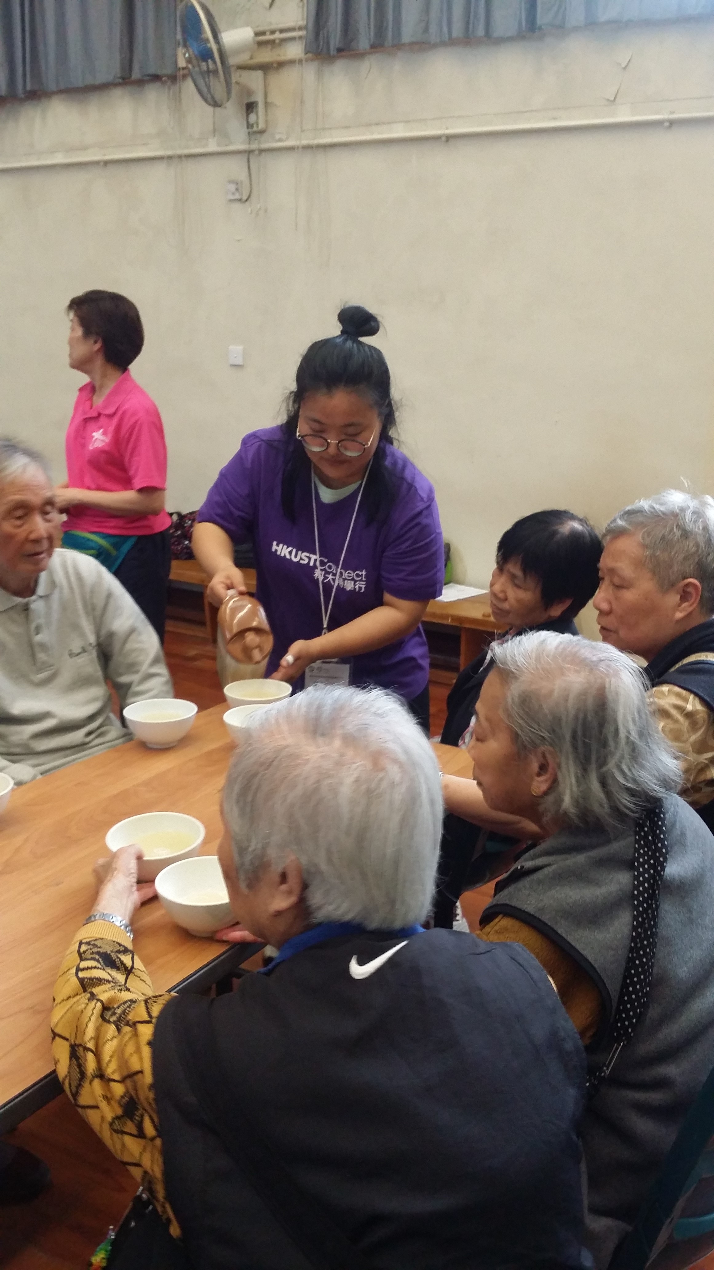 A volunteer distributing chinese soup to the elderly.