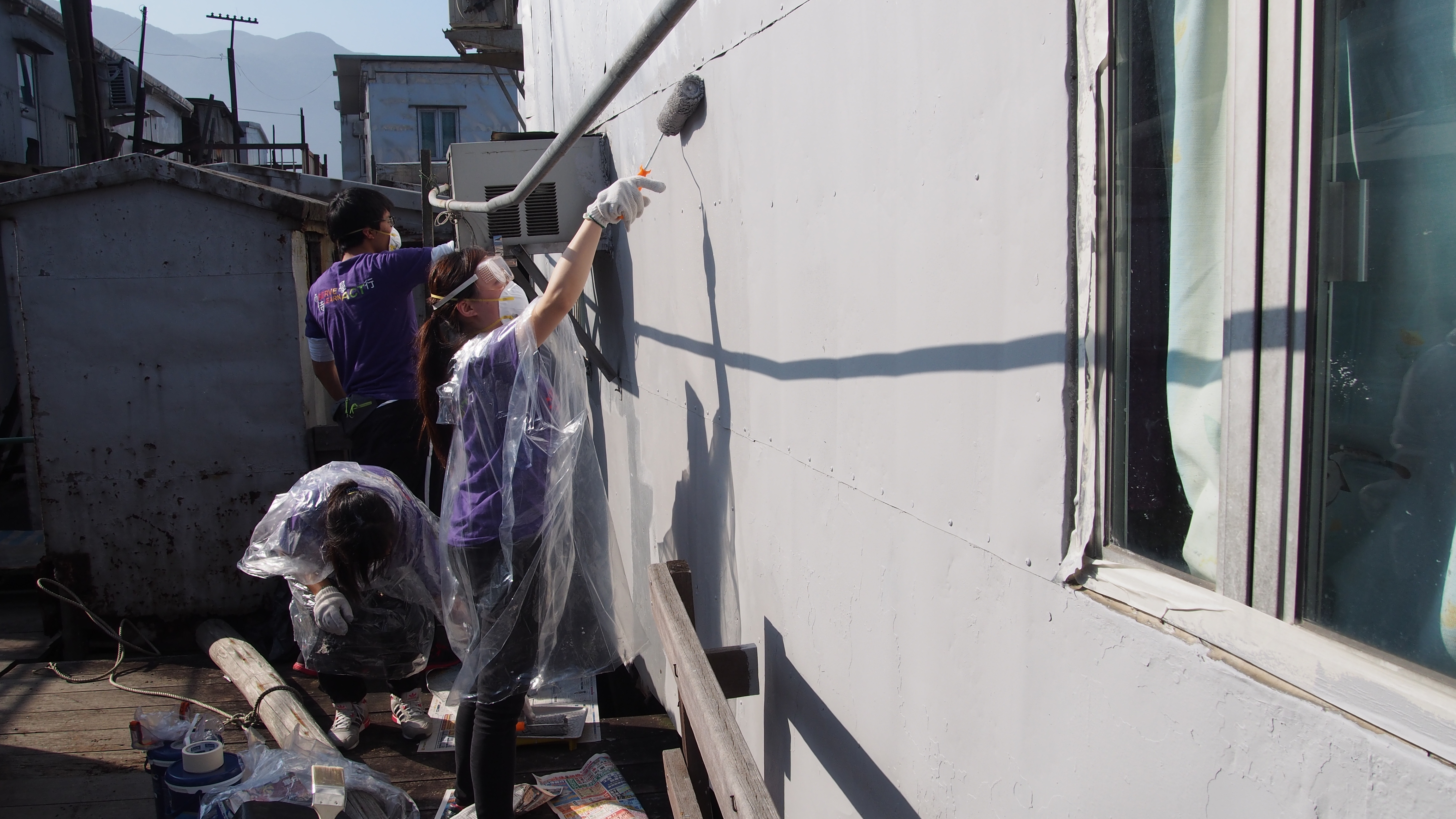 Volunteers painting the exterior wall of stilt house