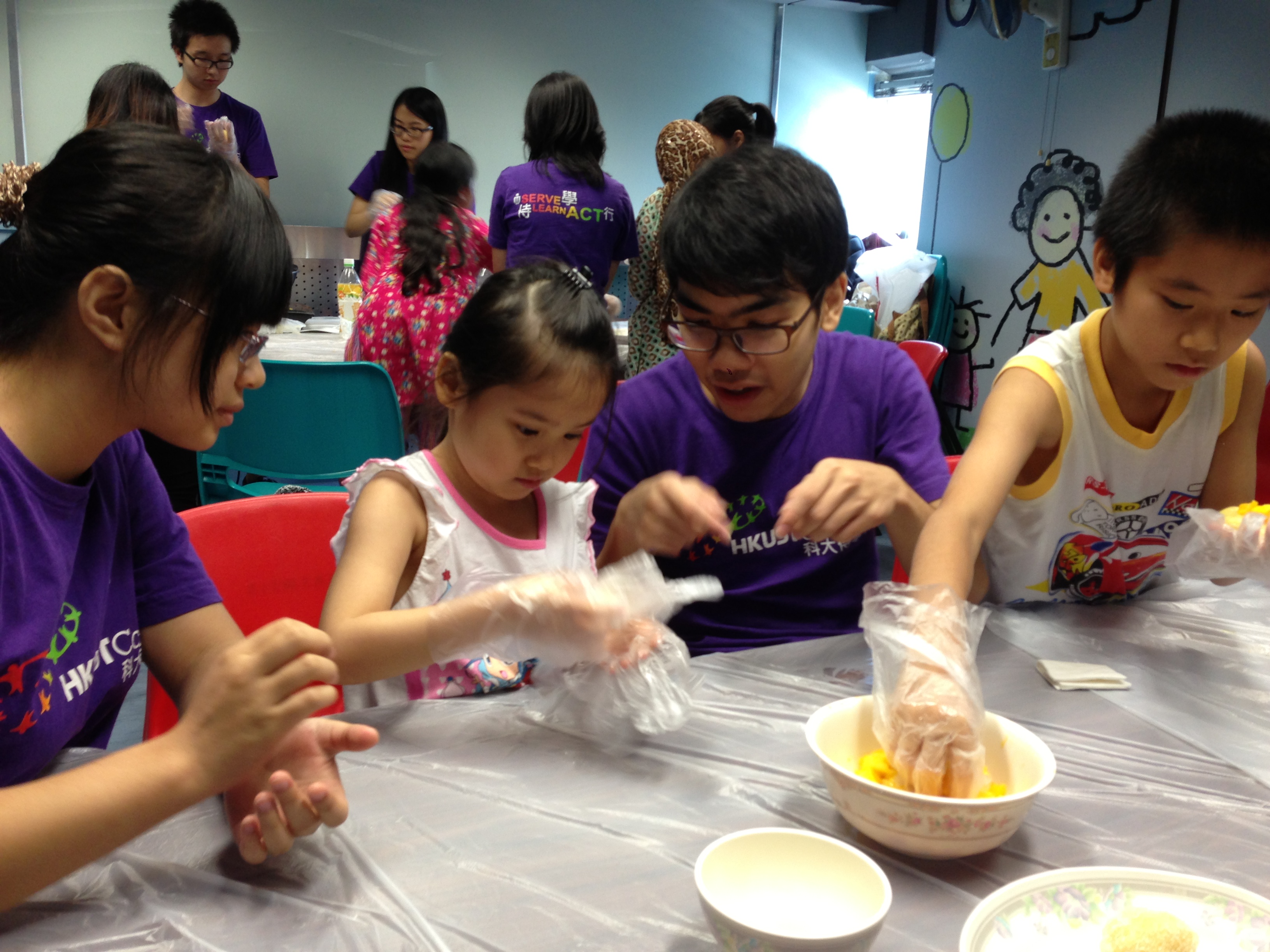 Volunteers and kids making mango dumplings together