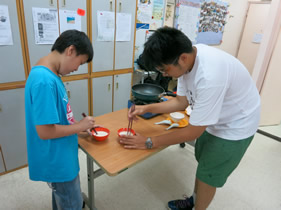 Volunteer guiding the child to cook