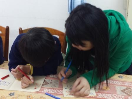 Volunteers drawing Christmas cards with the children