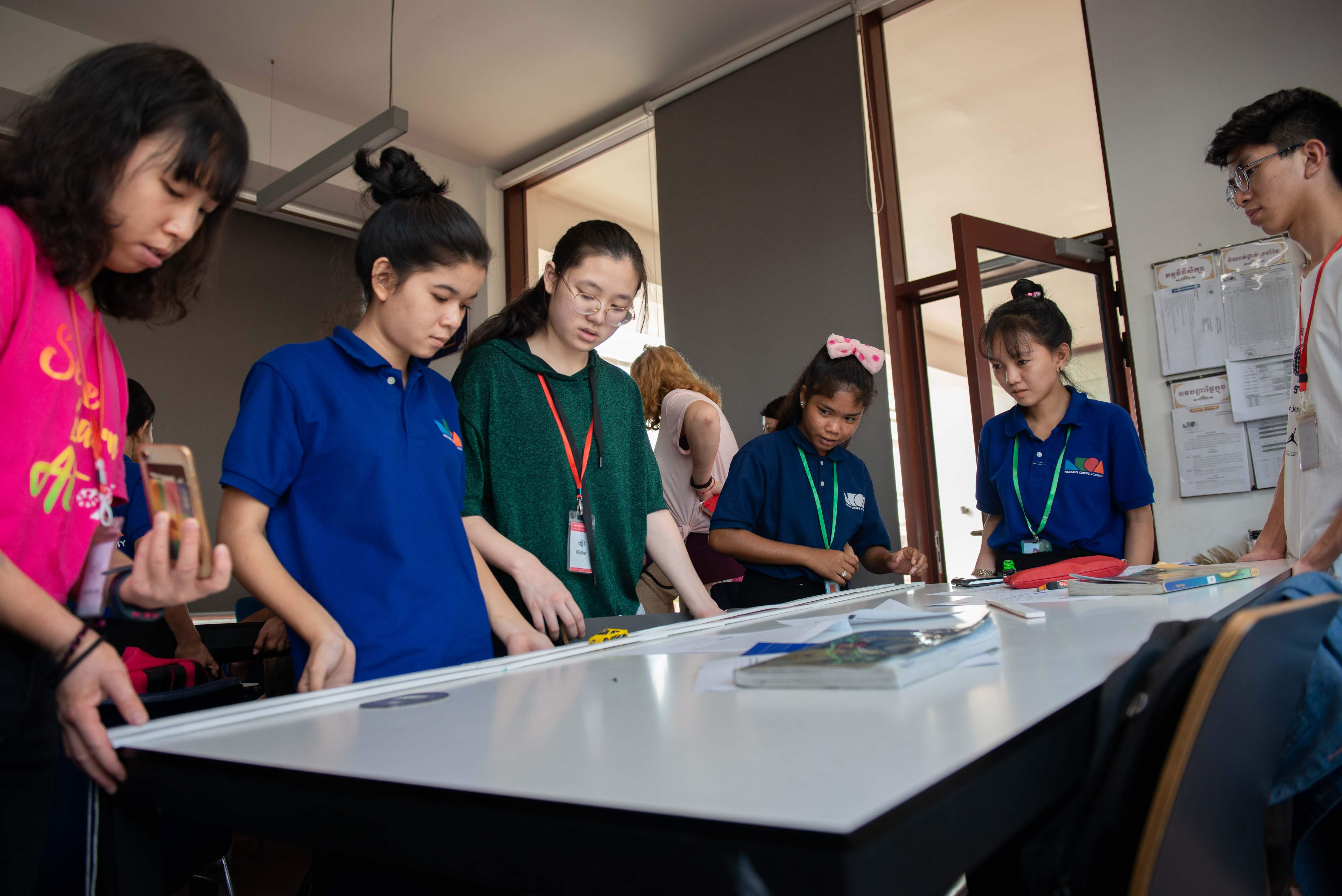Volunteers demonstrating the theory of inclined planes by releasing a toy car on the table lifted up on one side