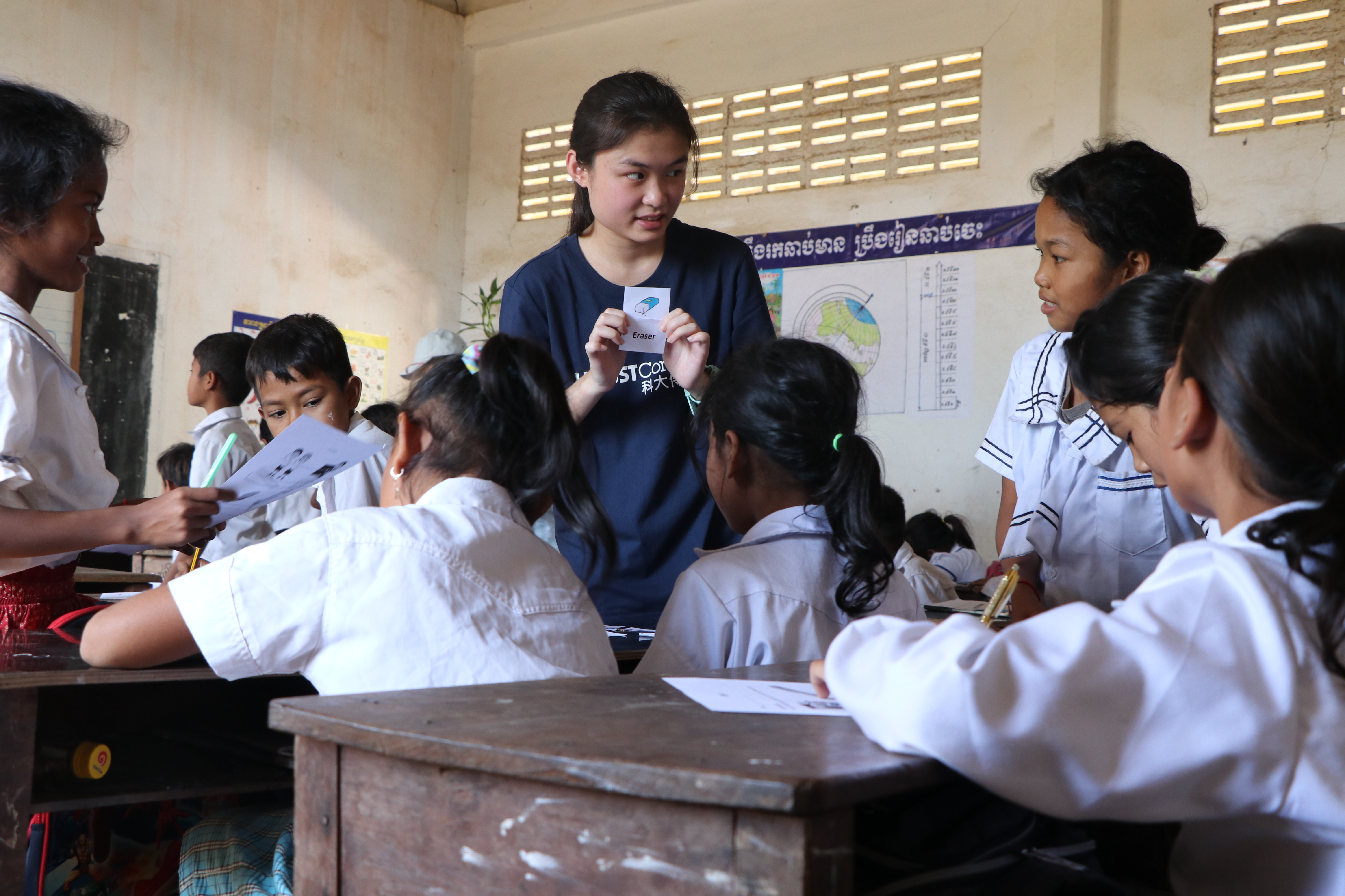 Volunteers teaching English class in the primary school and showing flash cards to students