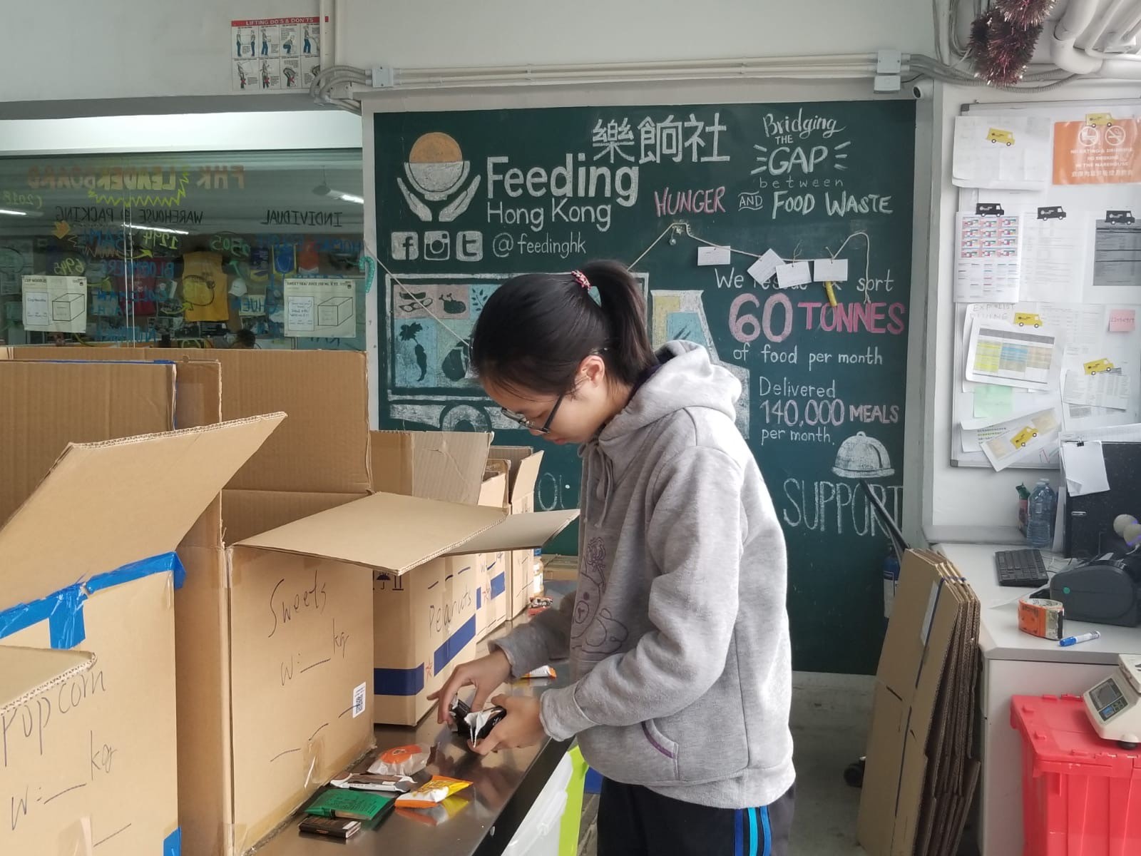 A volunteer stood in front of boxes of donated food and examined food packages to check their expiry dates 
