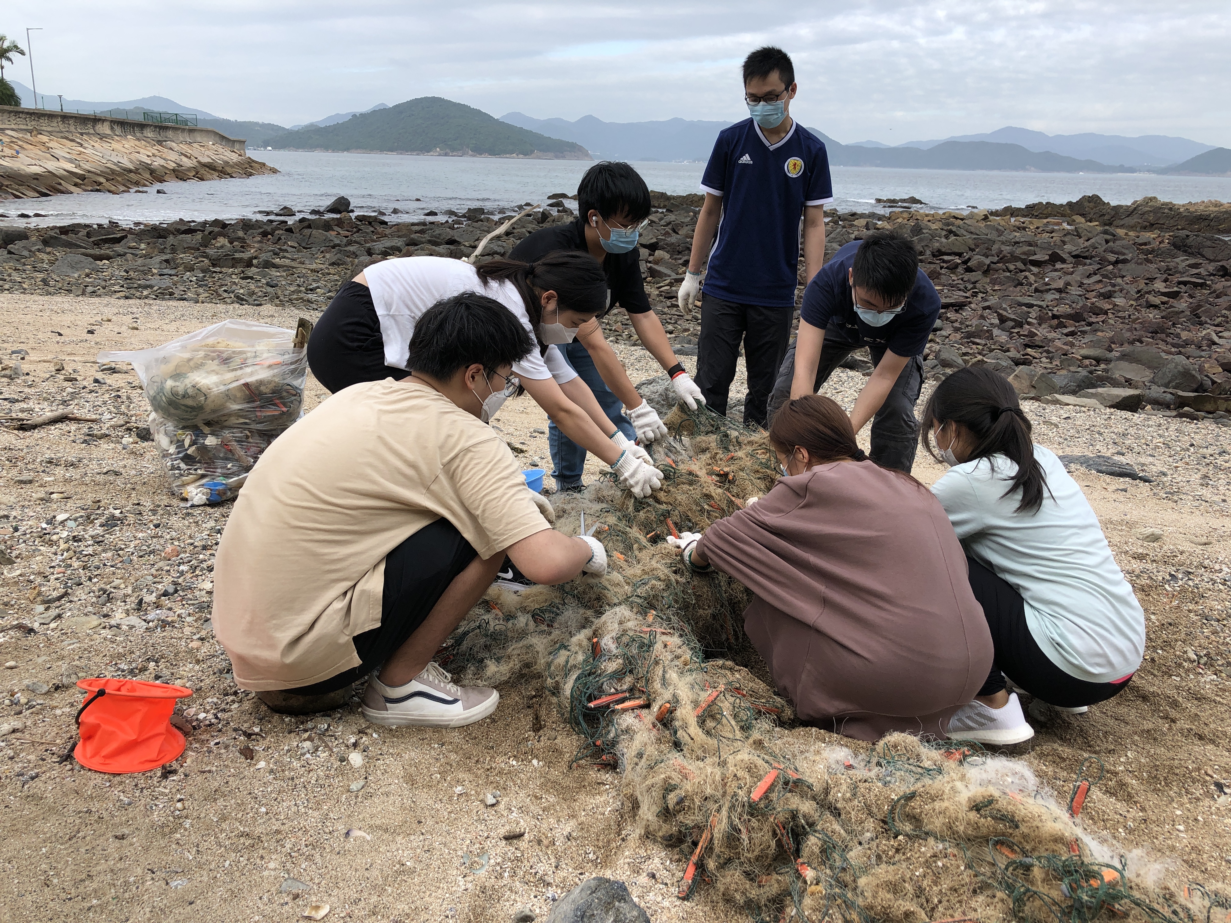 Students cleaning the abandoned fishing net on the beach