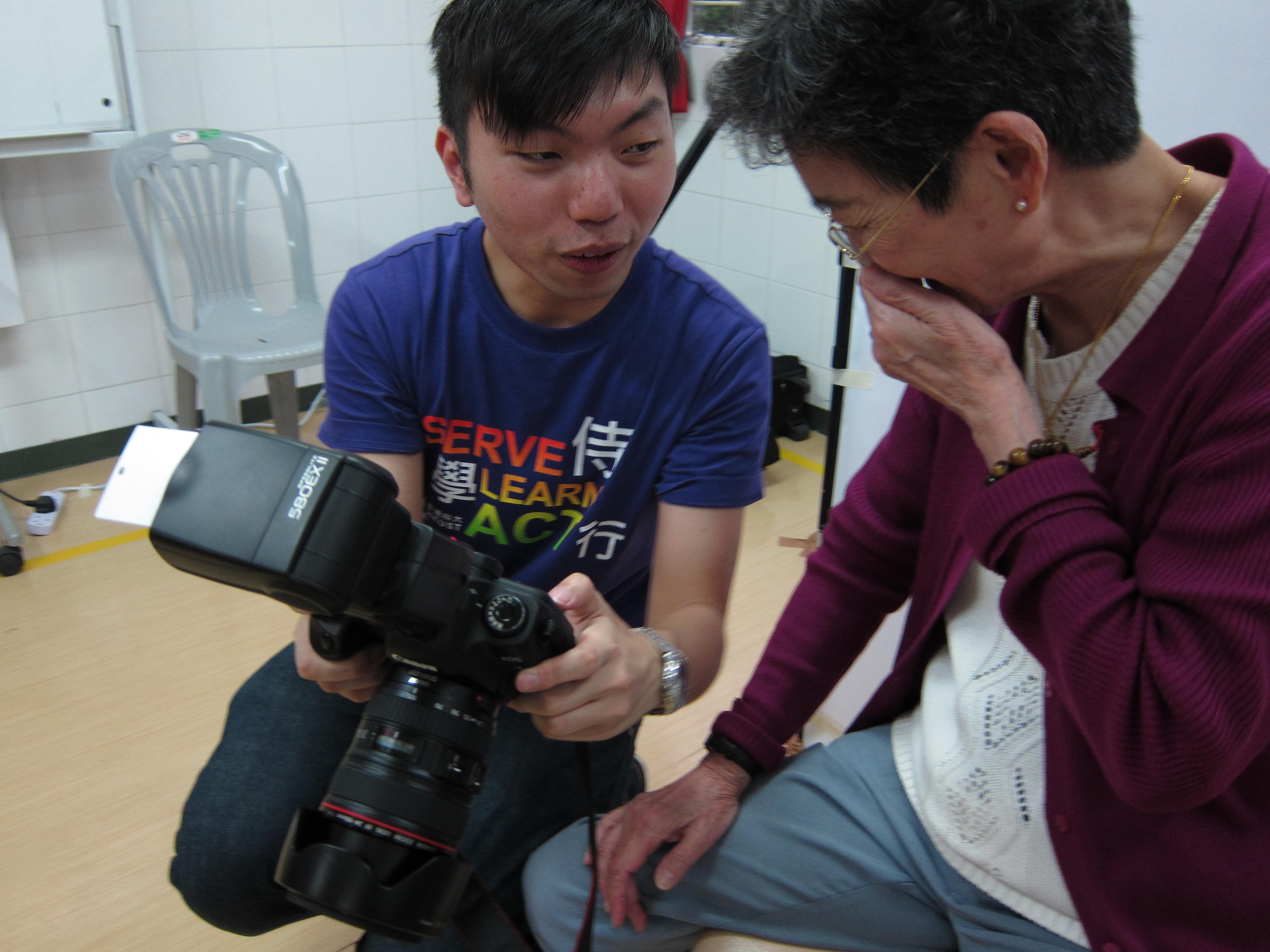 elder smiling covering her mouth as she looks at the photo taken on a camera