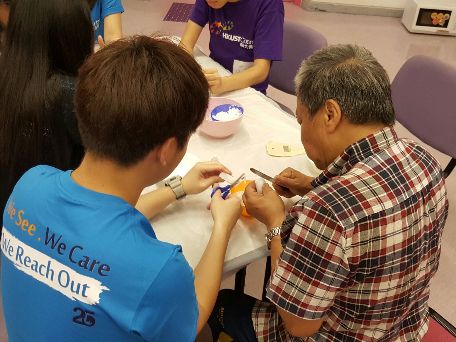 Volunteer assisting a visually impaired person with his artwork.  