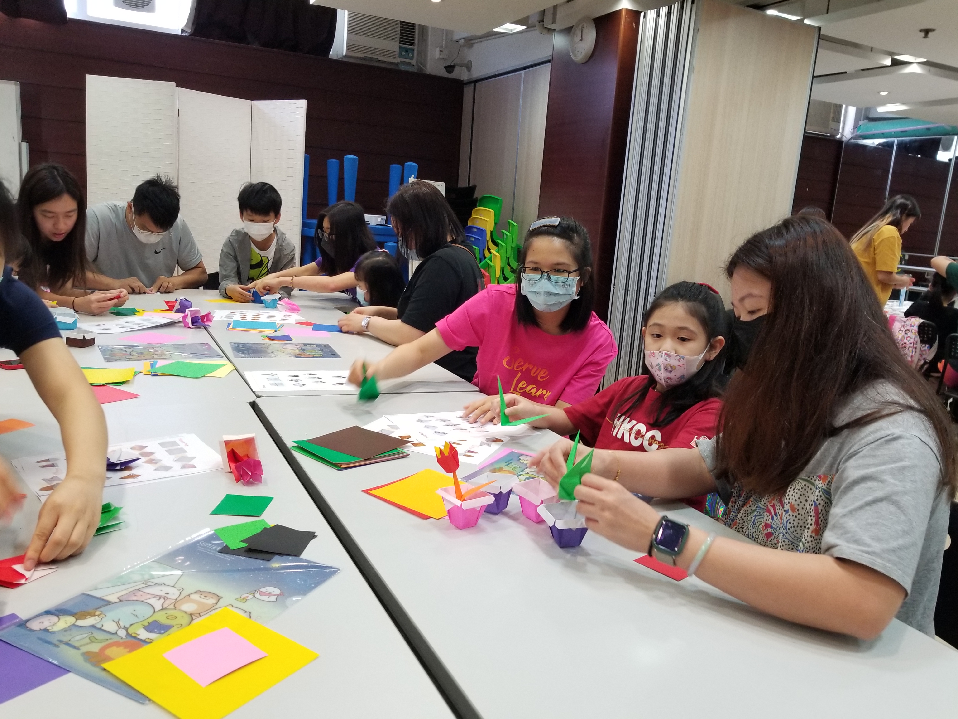 Volunteers teaching families to make an origami flower pot