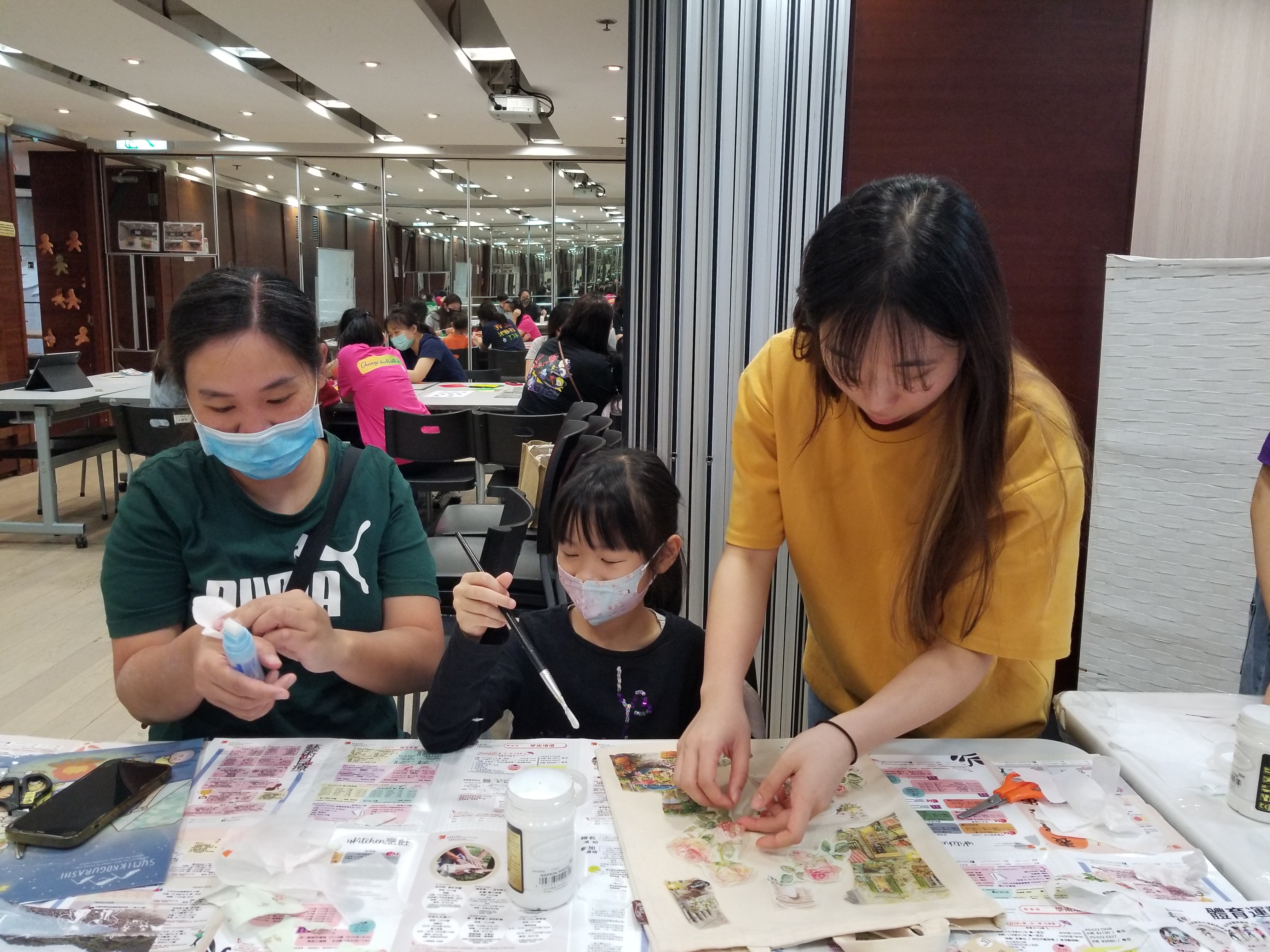 Volunteer guiding families on making a decoupage tote bag