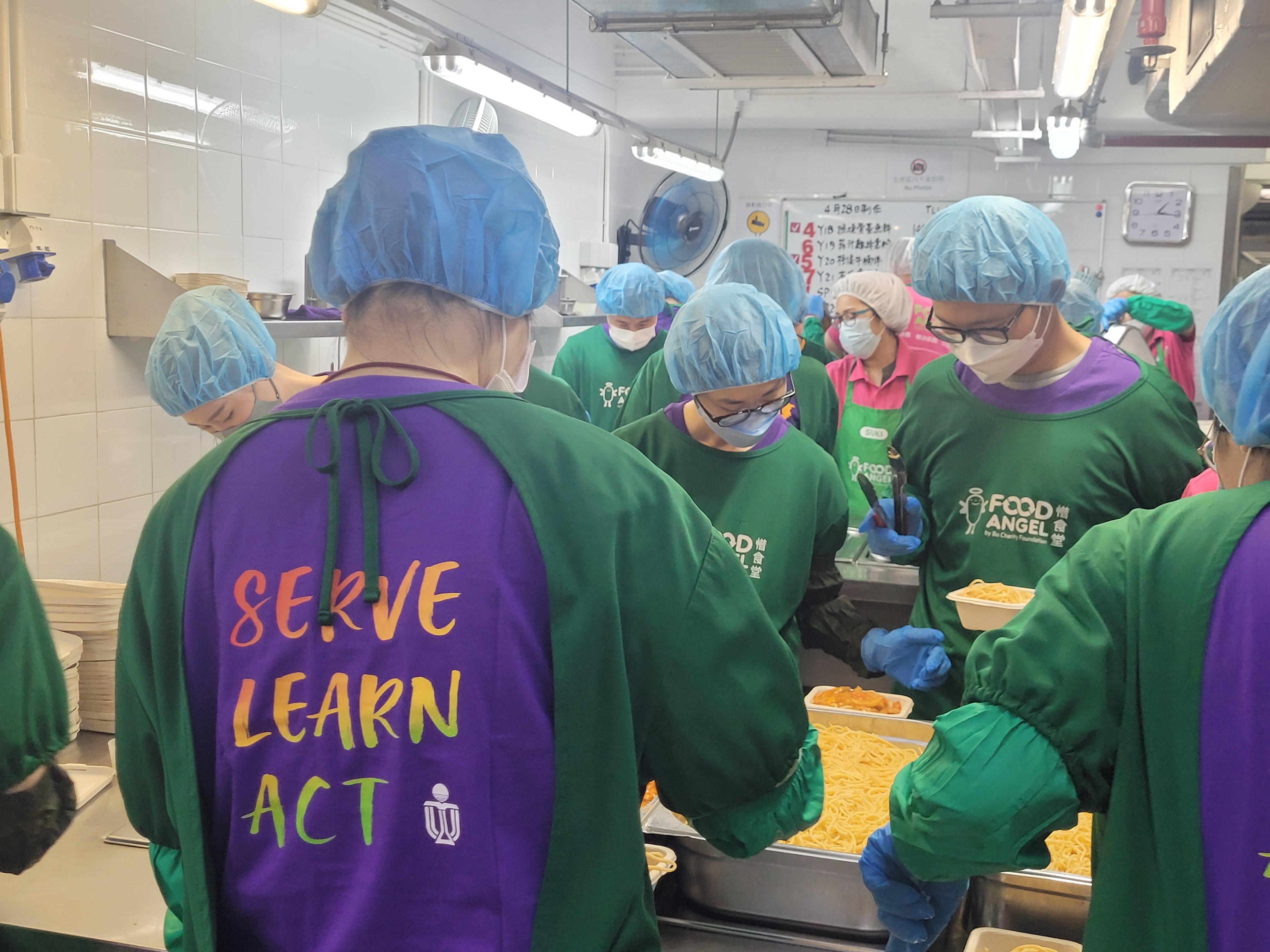 Volunteers in protective gear packing pasta into meal boxes