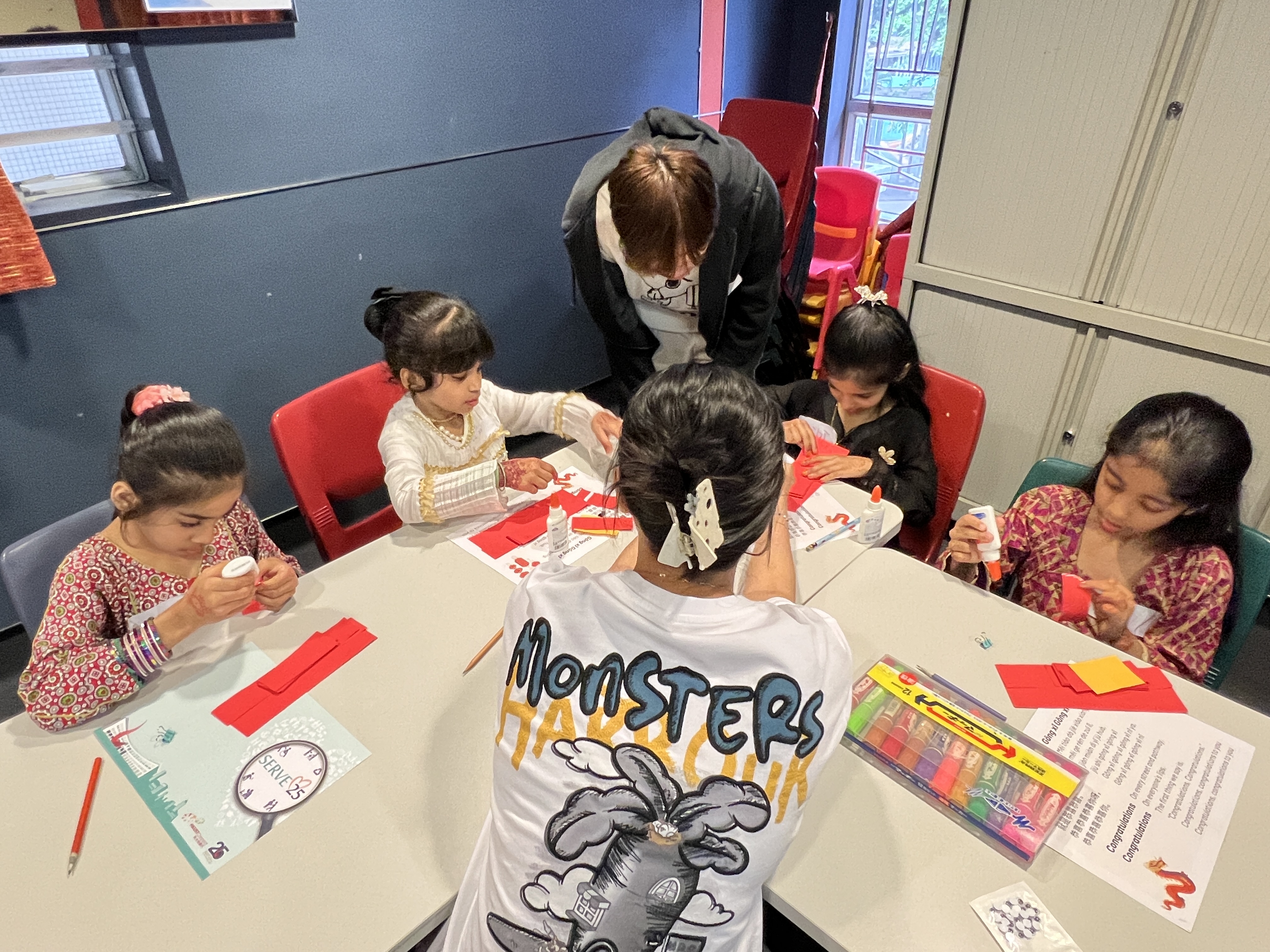 Volunteers teaching children how to make paper dragons.