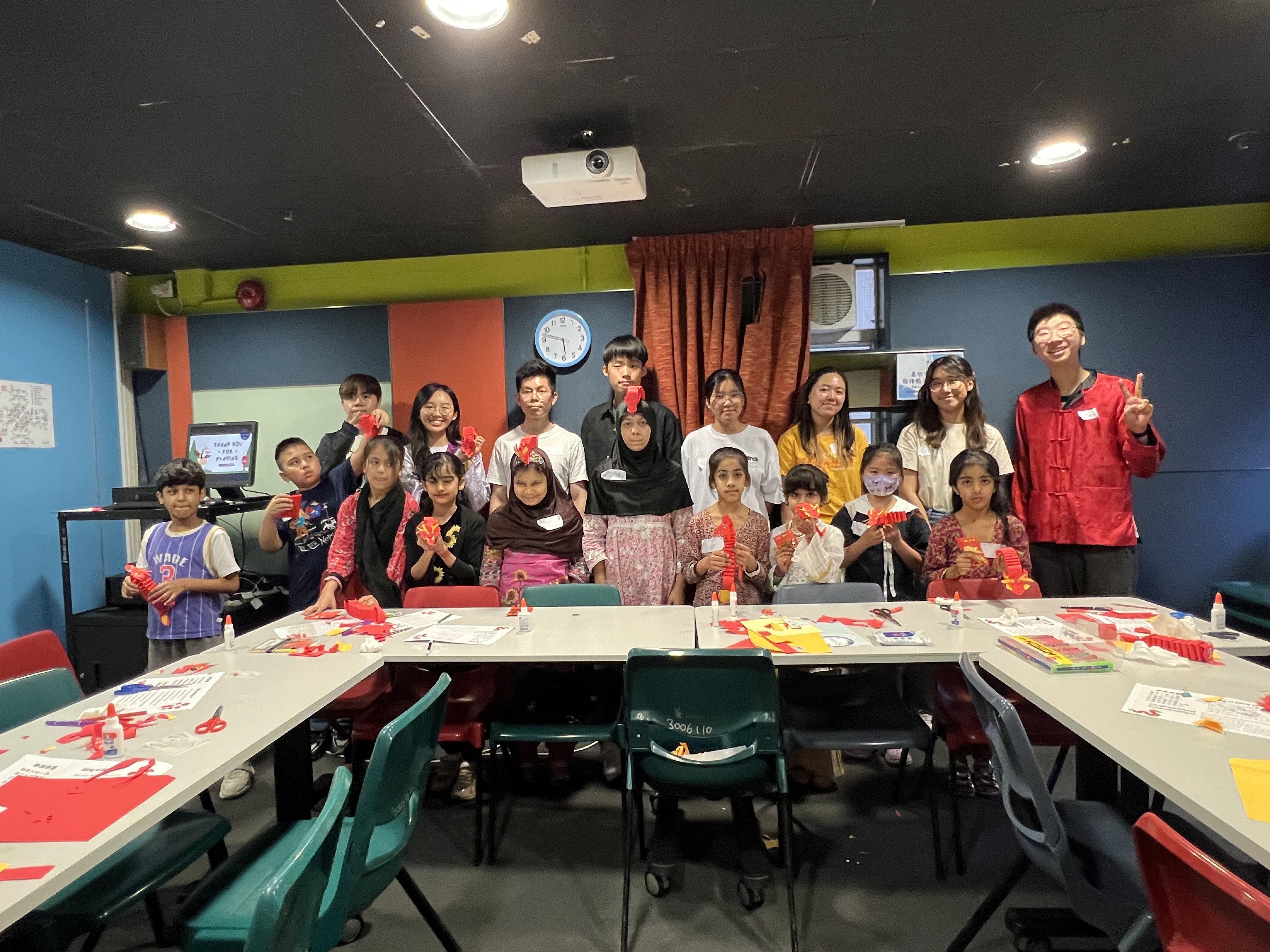 Volunteers taking pictures with the children holding up their paper dragons.