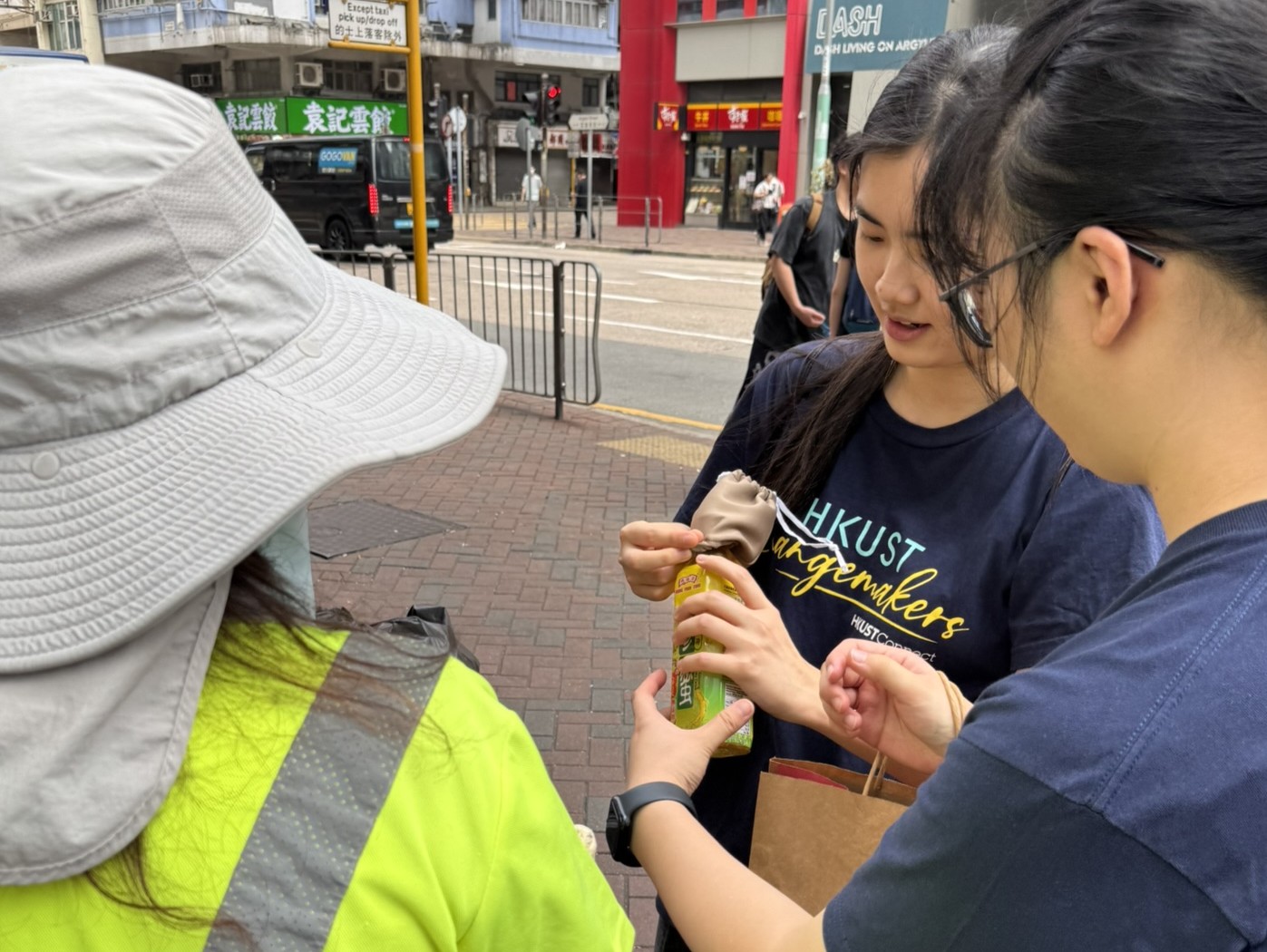 Students distributing water bottle covers to street cleaners