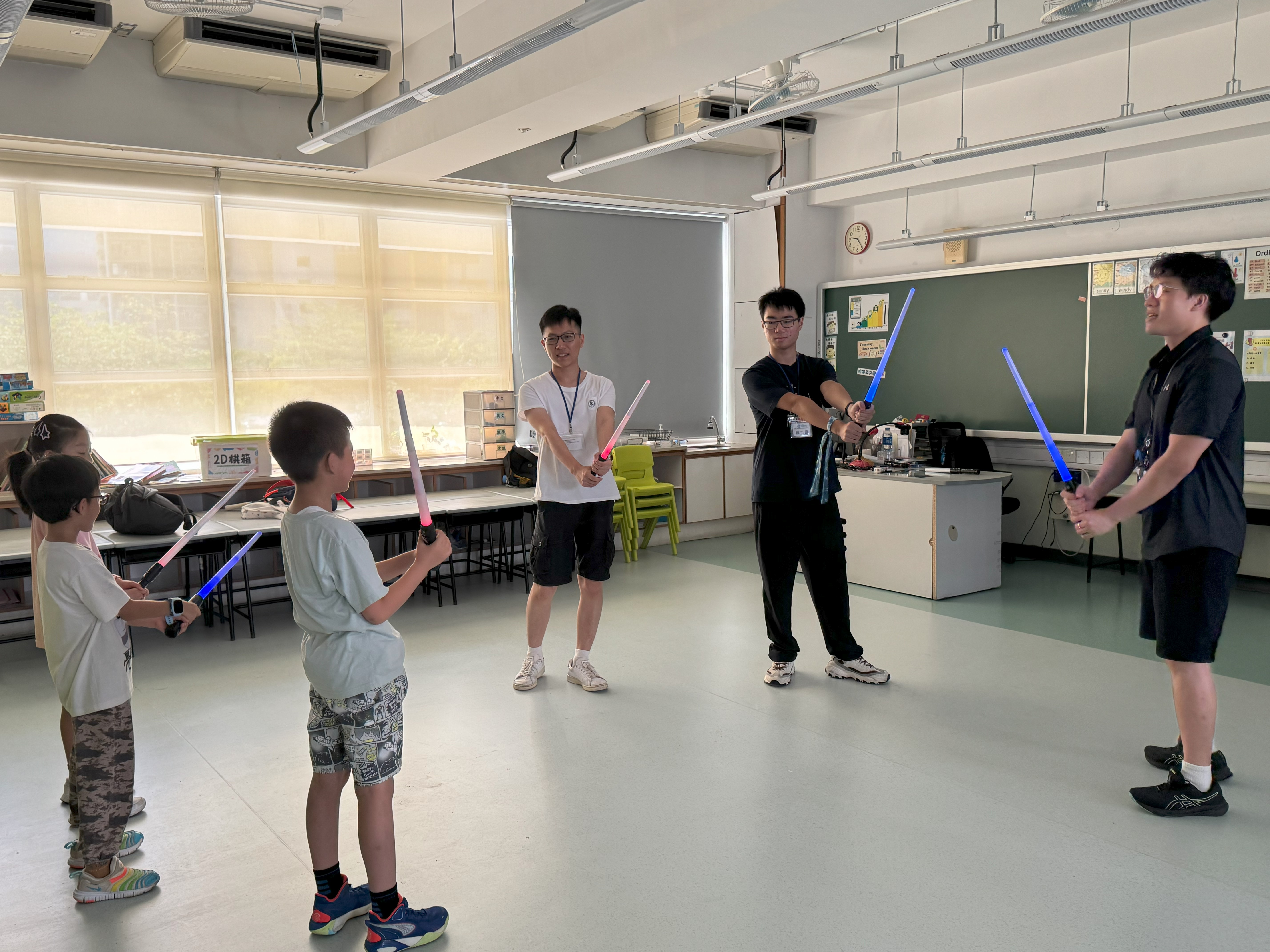 Volunteers instructing children on lightsaber techniques