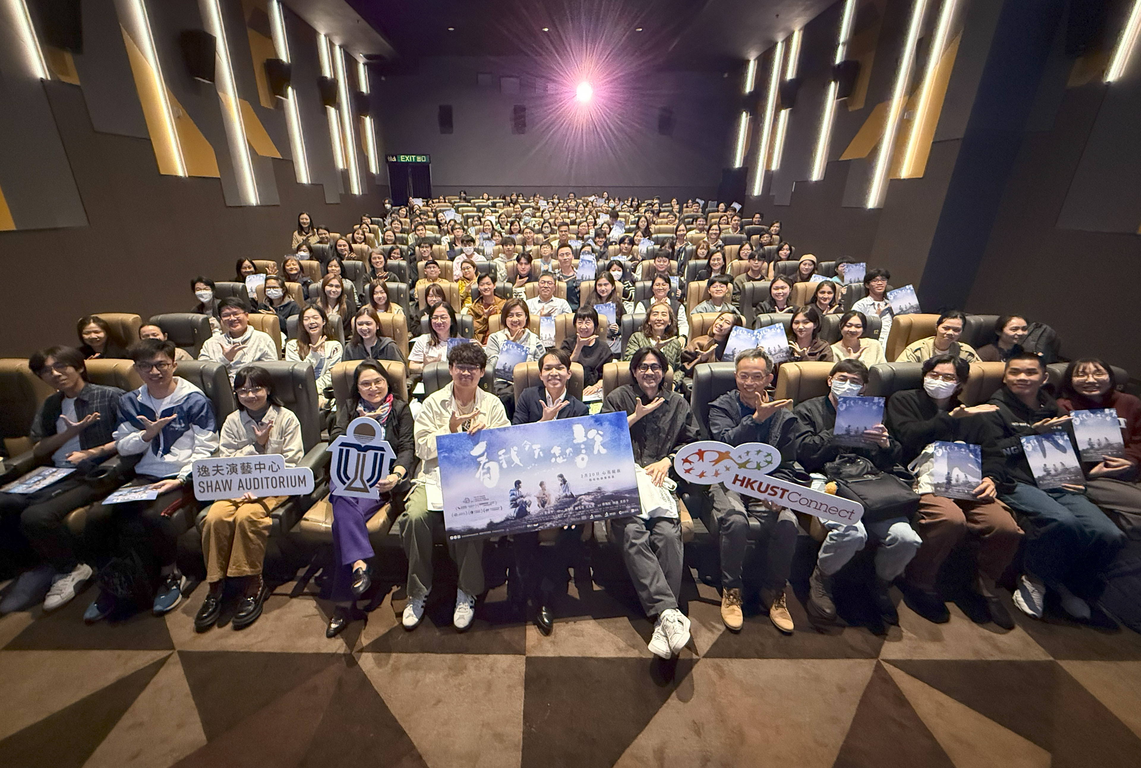 Participants and movie crew members taking a group photo with sign language