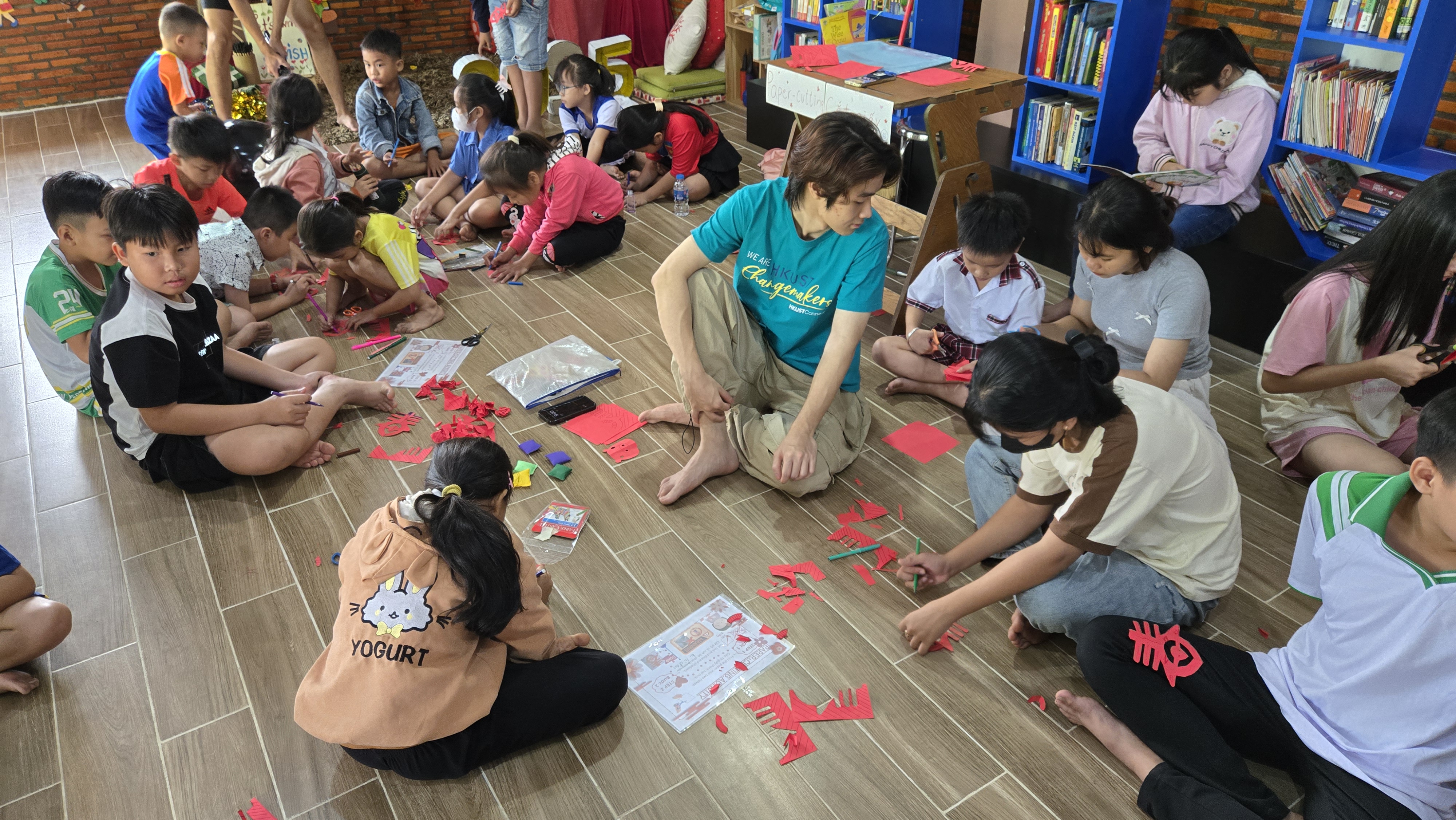 Volunteer teaching children traditional Chinese paper-cutting art in community carnival