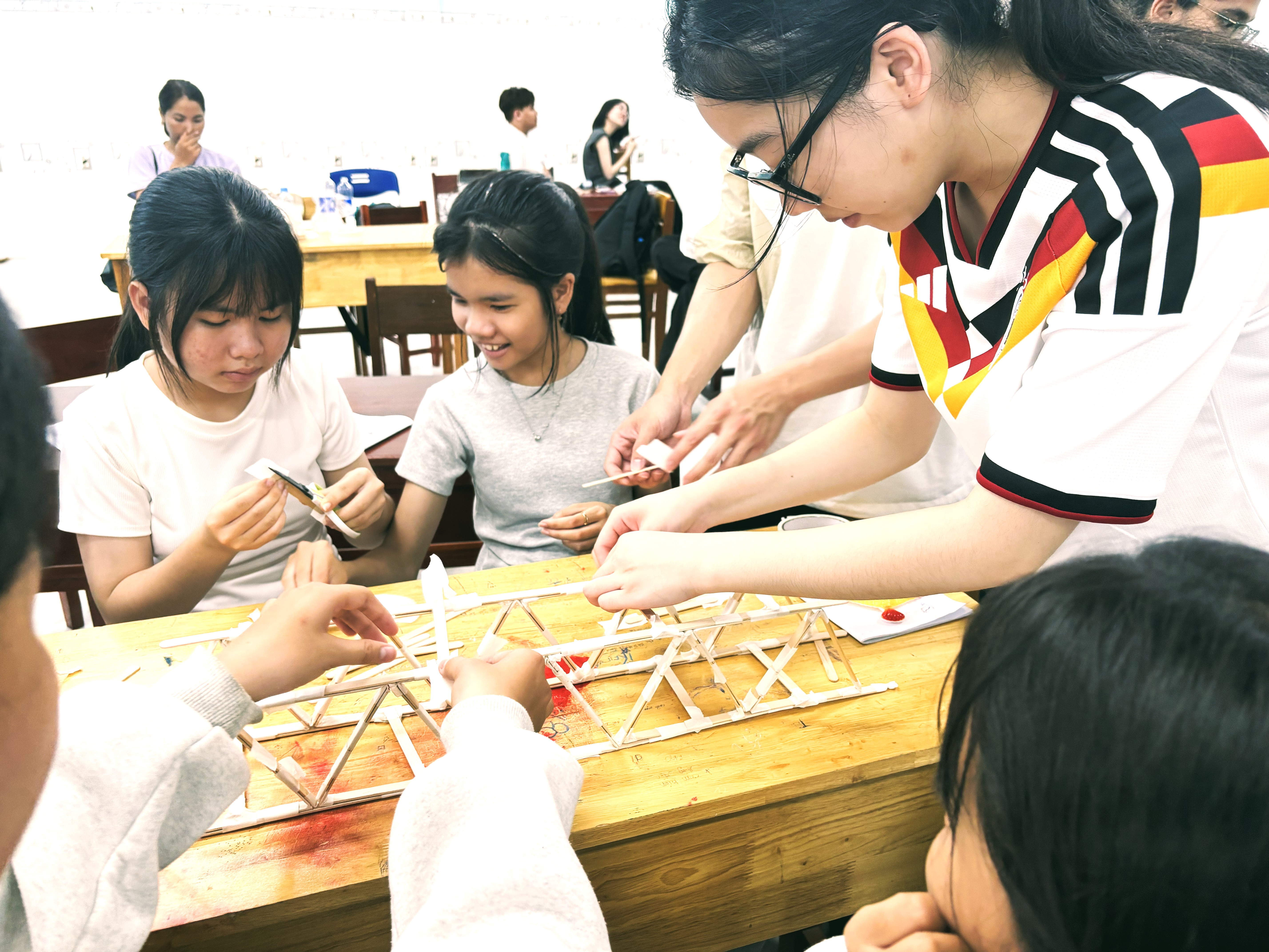 HKUST students facilitating in a STEM activity, guiding secondary school students to build wooden stick bridge