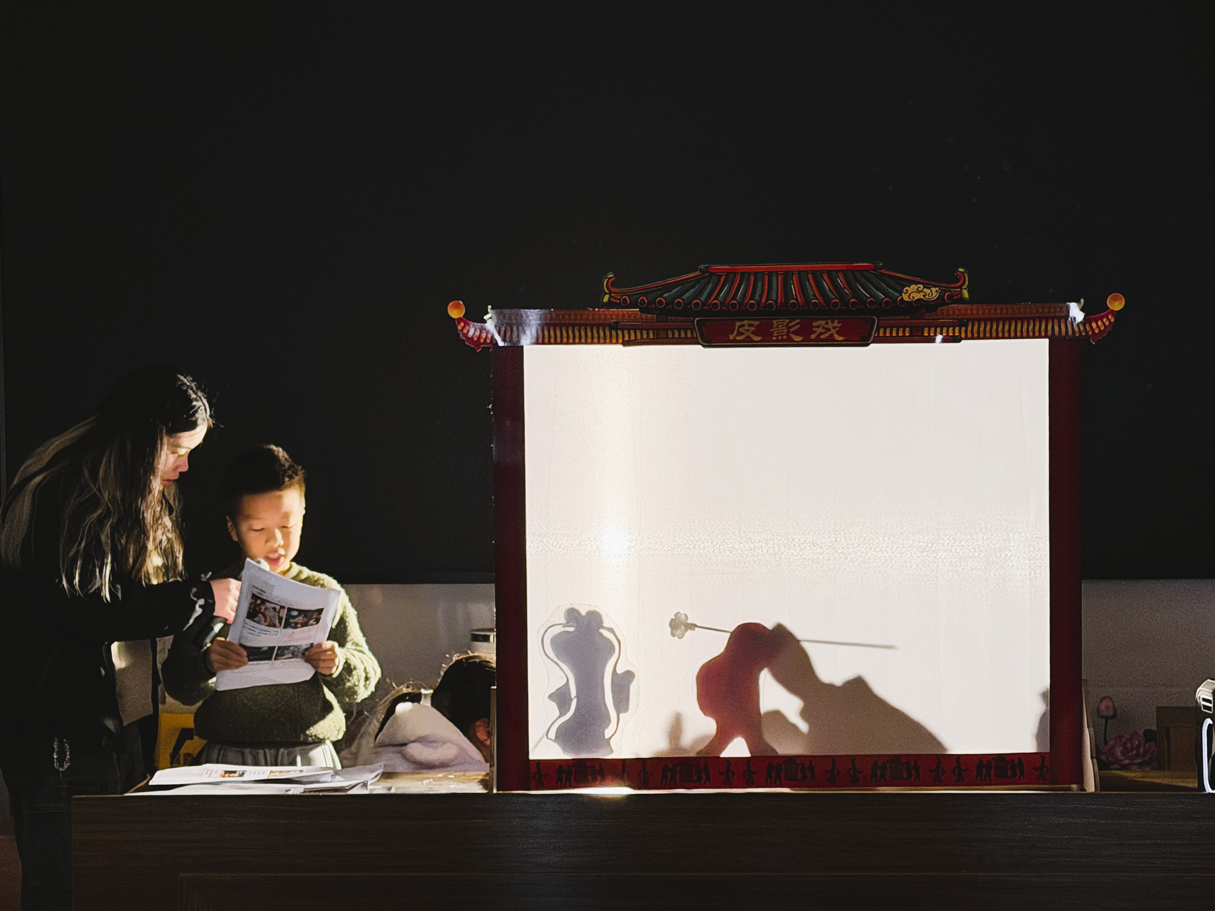 Volunteers guiding children in the art of shadow play.