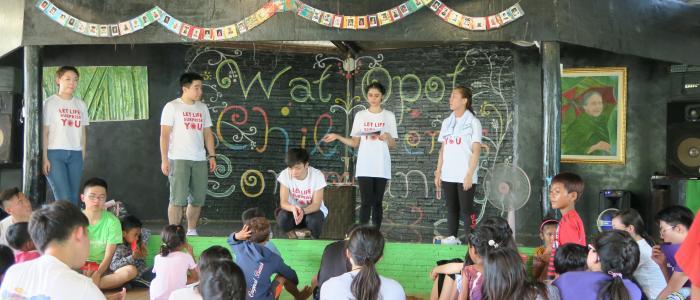 4 volunteers teaching in front of a group of kids
