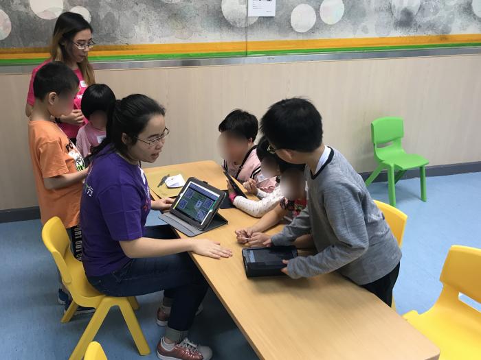 Volunteer guiding children to use tablets to play the games