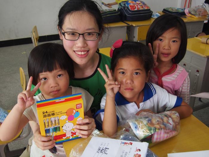 Children receiving stationary supplies and daily essentials from a volunteer