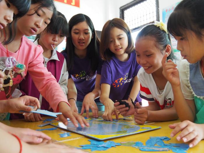 Volunteers guiding the children to finish a "world map puzzle"