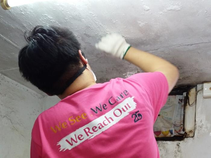 A volunteer fixing a peeling ceiling
