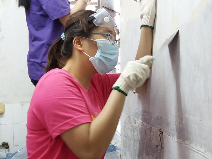 Volunteers removing uneven wall plastering