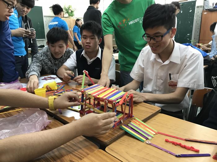 A group of students working together to build a model by using some wooden sticks