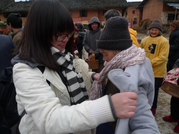 A volunteer distributing second-hand clothes to the elderly