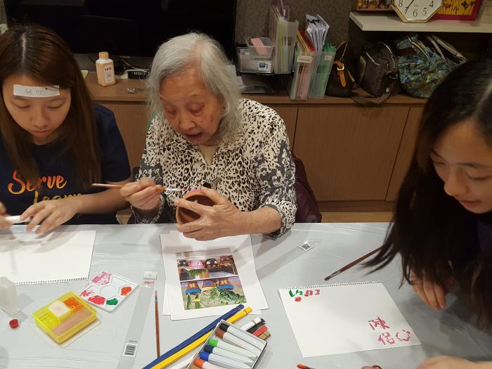 Volunteer and elderly making pot decorations