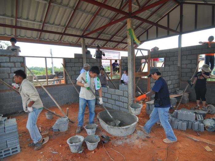 Student volunteers mixing cements and laying bricks